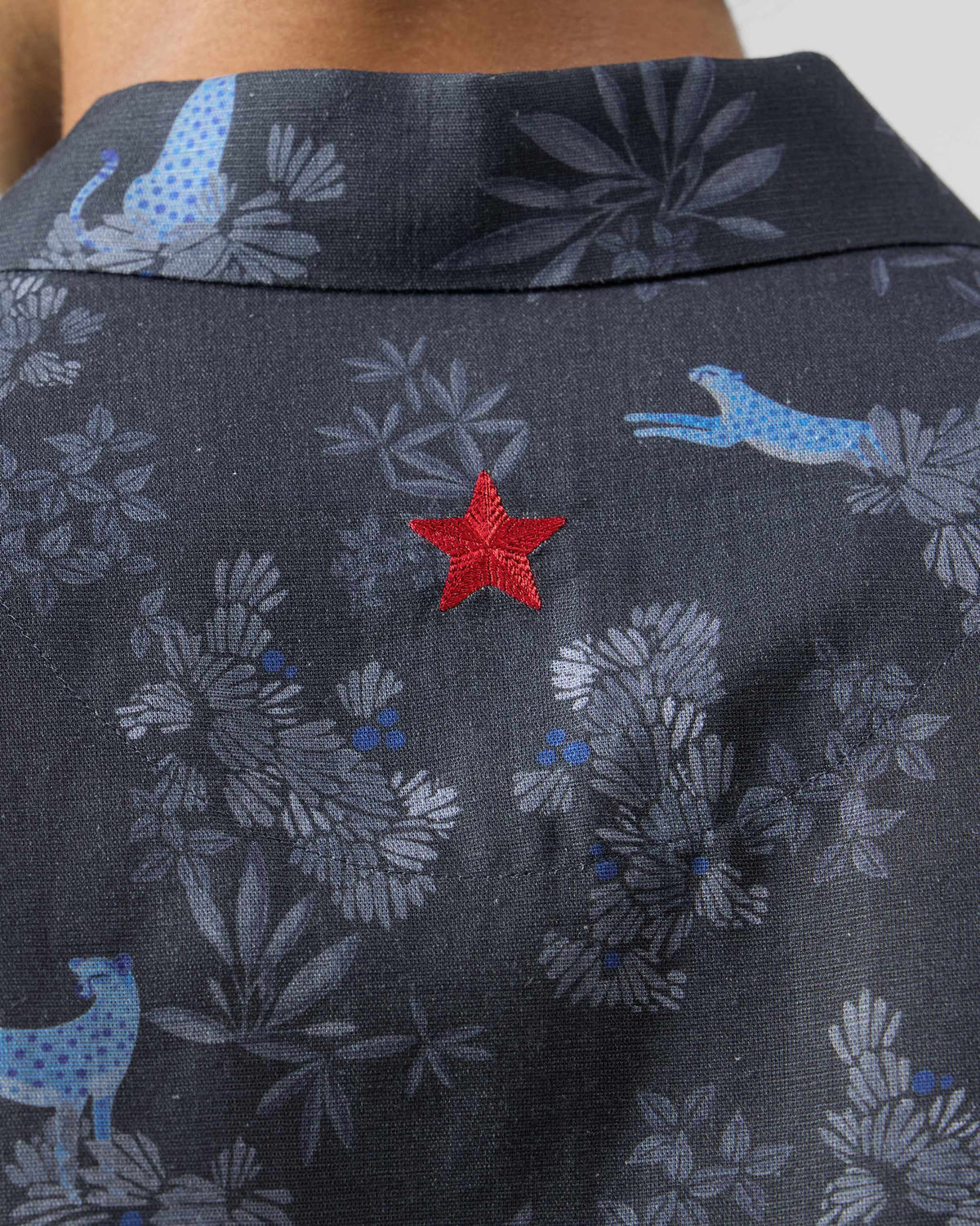 Close-up of the red embroidered star on the back of a charcoal Mistari Shirt.