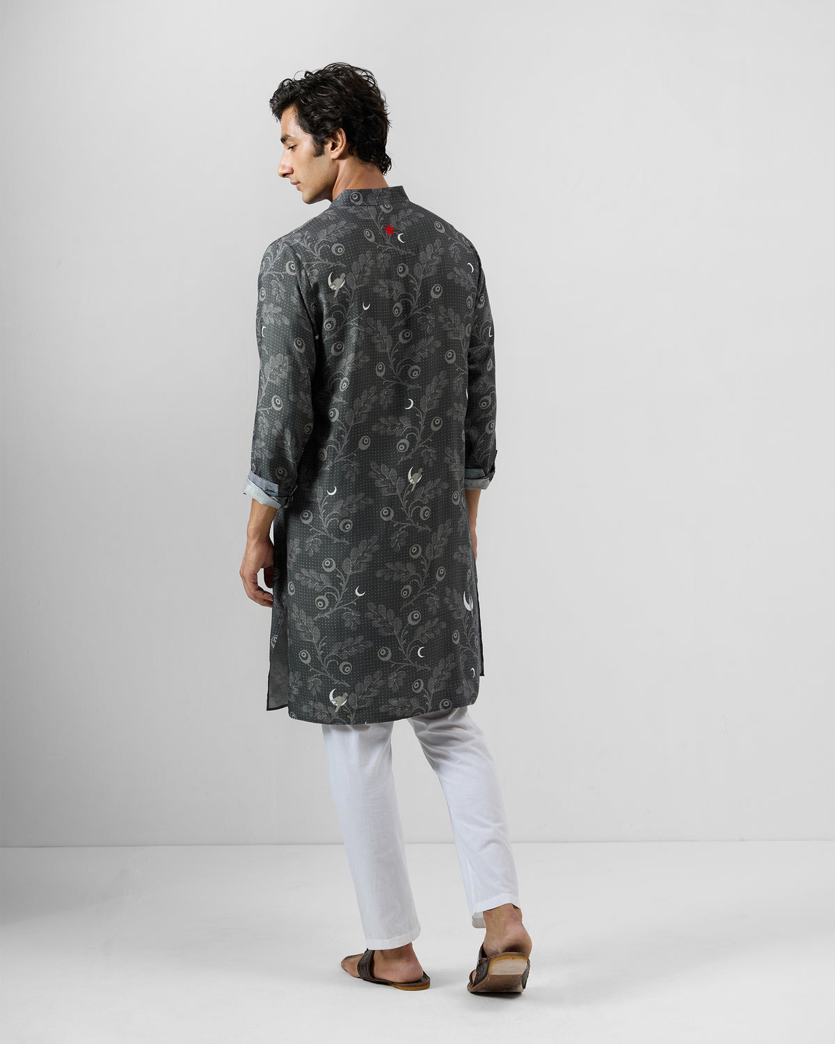 Back of a charcoal Rey Kurta with botanical print and a red embroidered mark.
