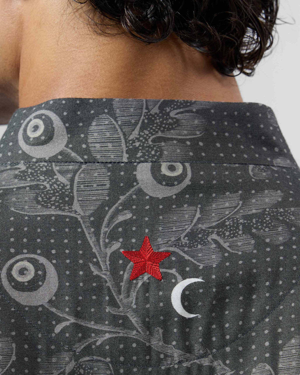 Close-up of a red star and white moon on the back of a charcoal Rey Kurta.