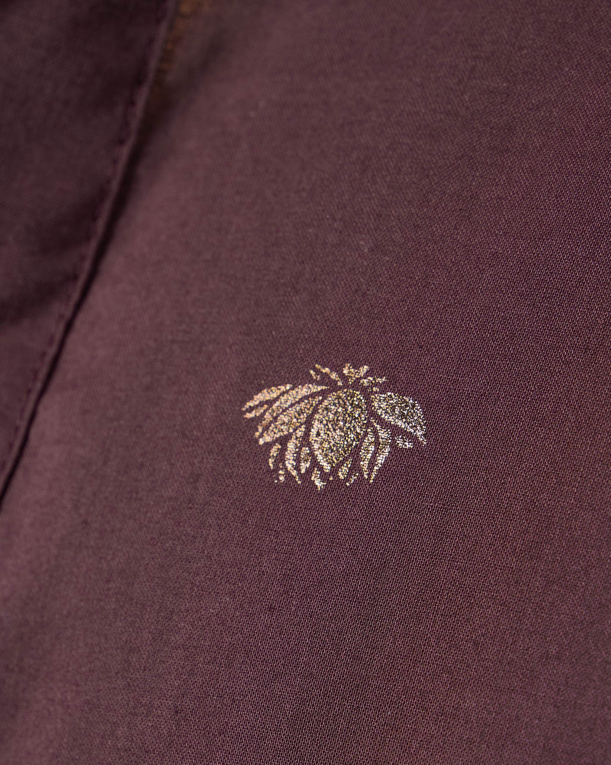 Close-up of a gold foil flower motif on a wine Rey Kurta.