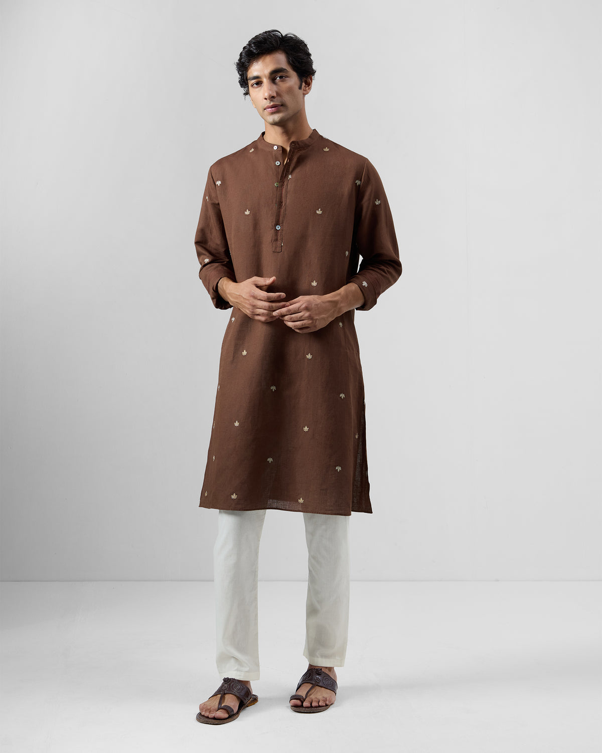 Person wearing a brown Astral kurta with all-over leaf embroidery.