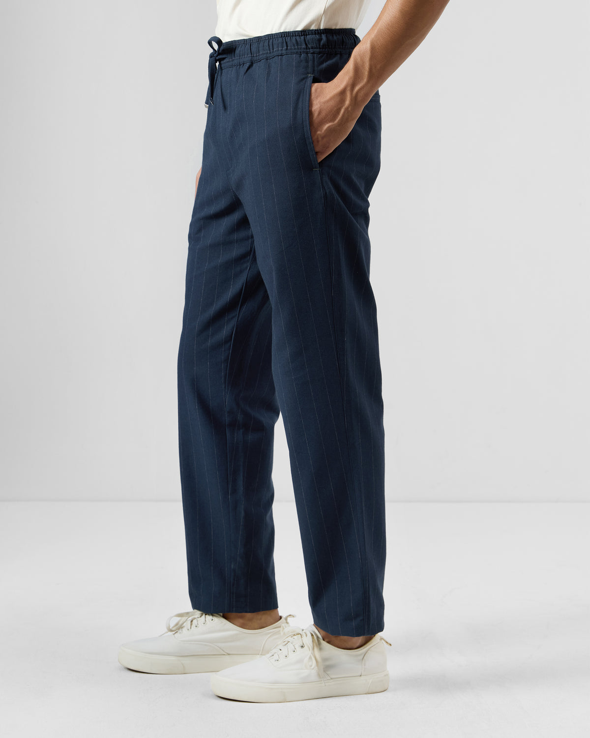 Side view of navy pinstripe Vera trousers showing the relaxed straight leg.