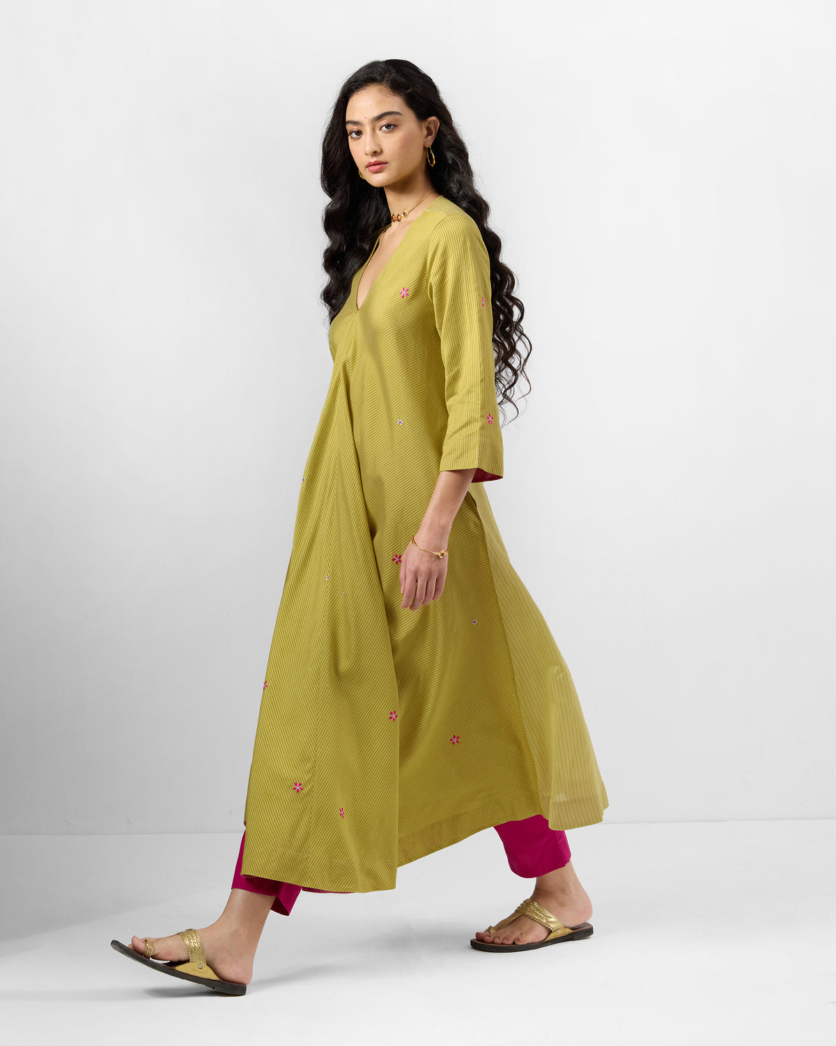 Side view of a sand Murud flared kurta with pink floral embroidery.