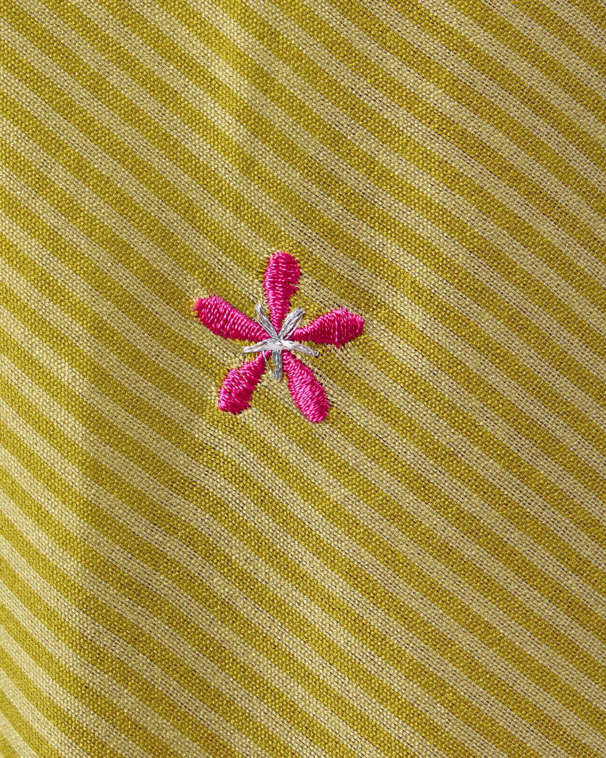 Close-up of a sand Murud kurta with a small pink embroidered flower.