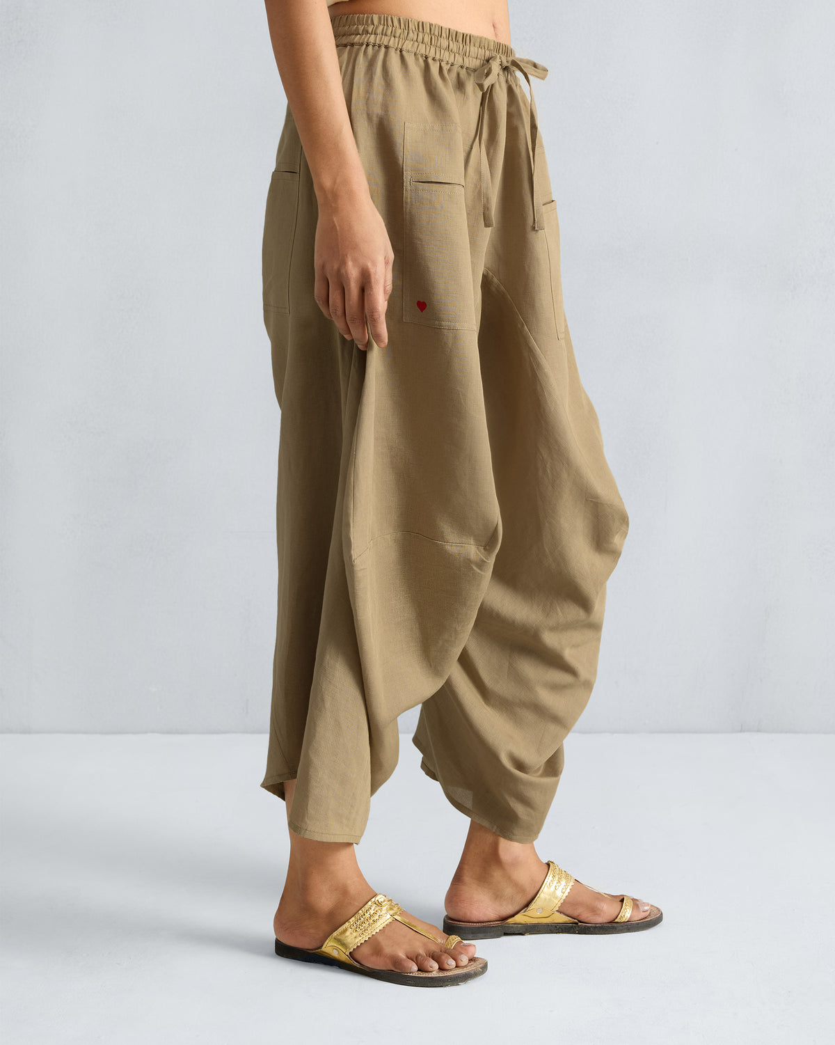 Side view of taupe Yoka Trousers showing a small red heart on the pocket.