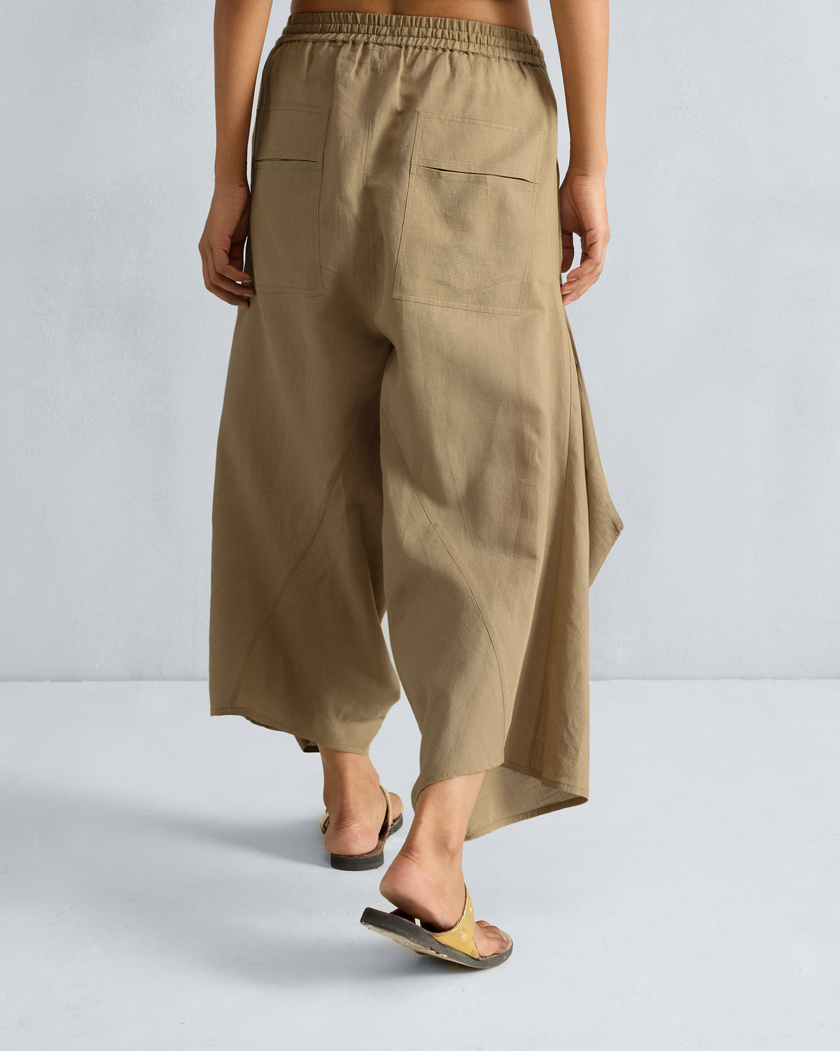 Back of taupe Yoka Trousers with patch pockets worn by a person.
