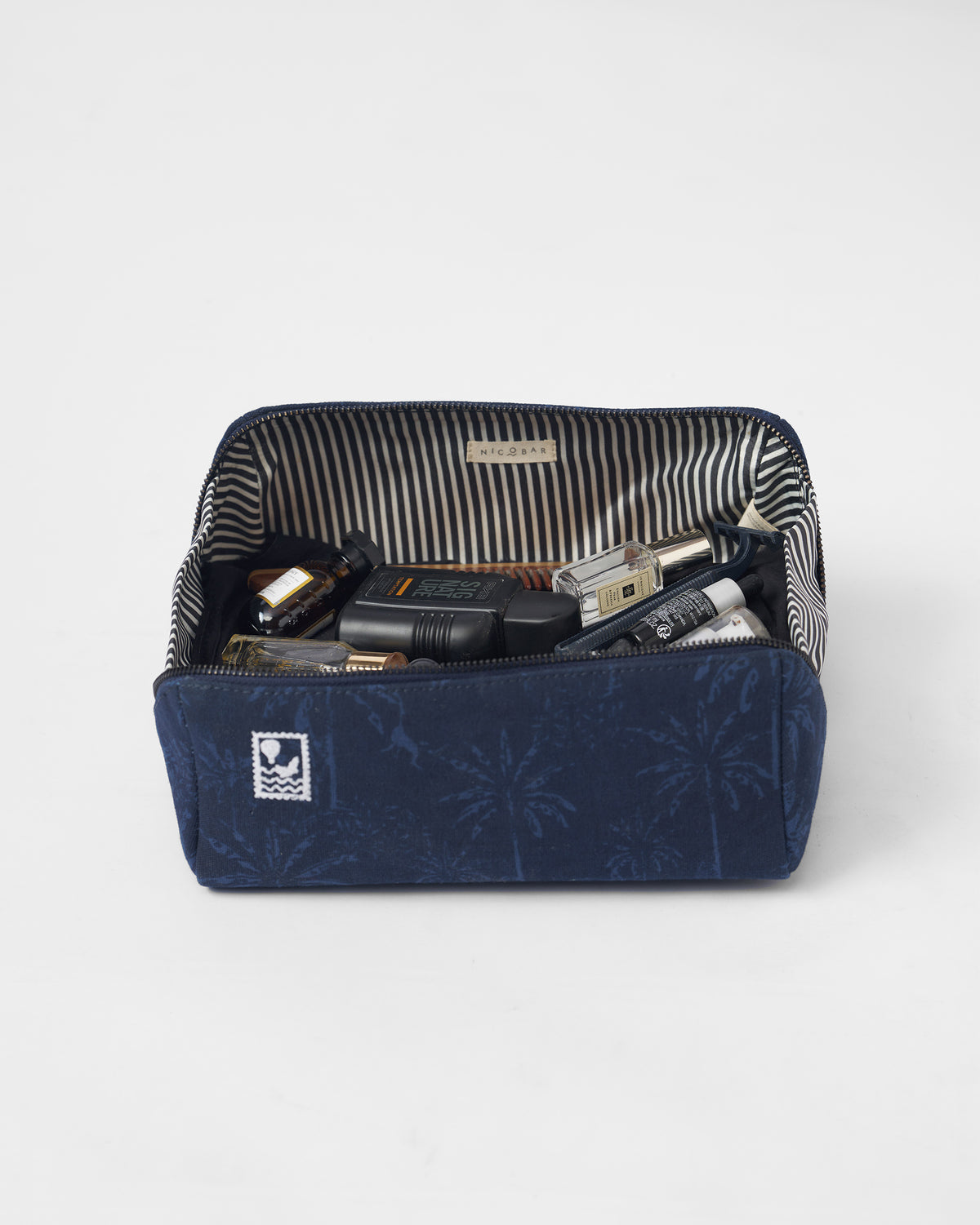 Open navy Palm dopp kit with a striped lining and toiletries.