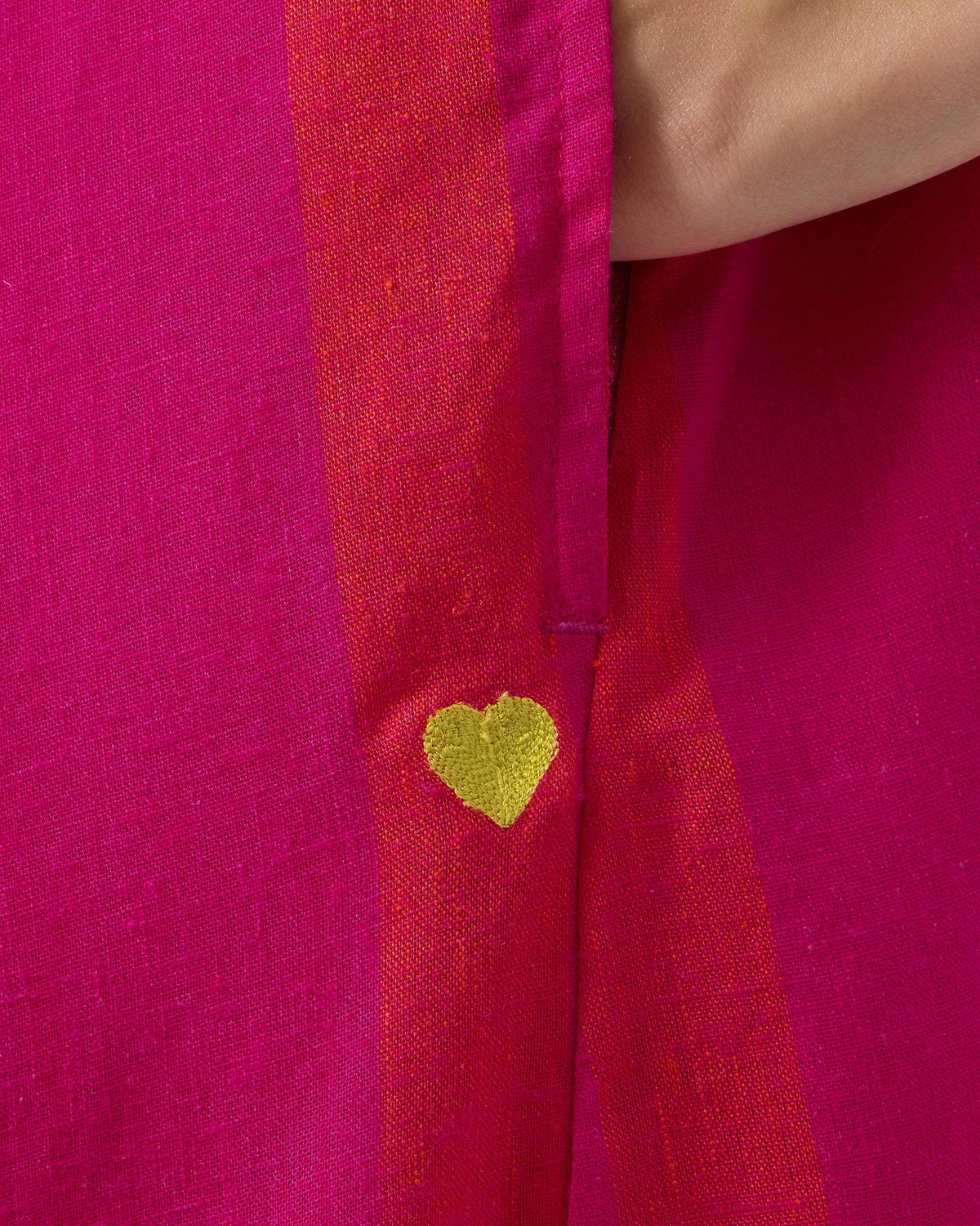 Close-up of pink and orange Narali dress fabric with a lime green embroidered heart.