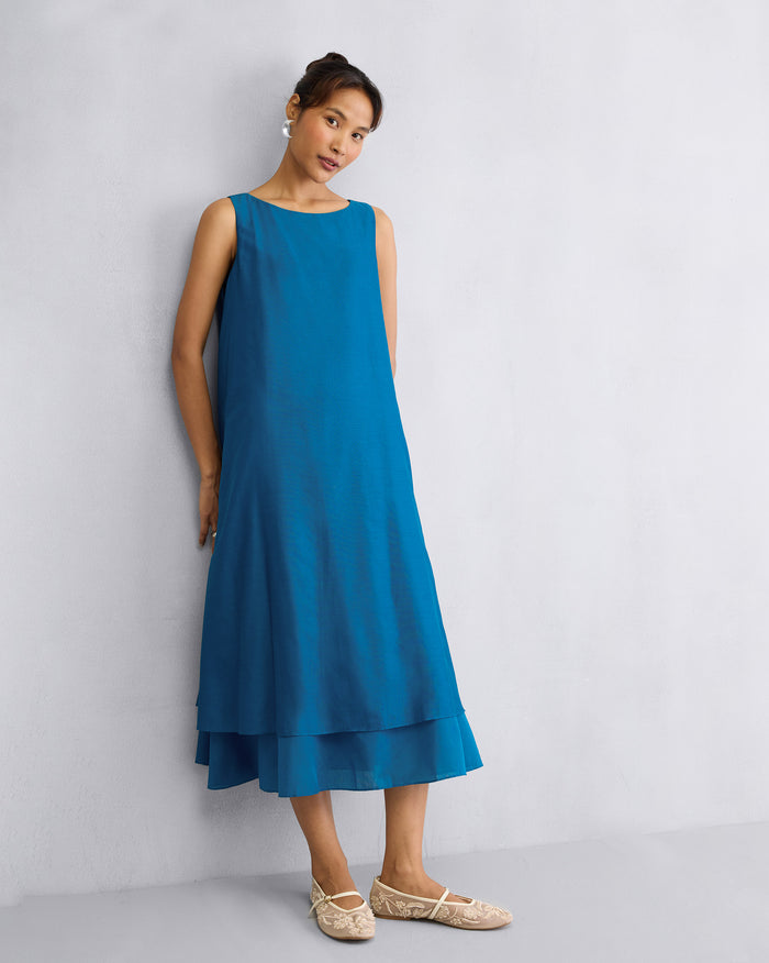 Person wearing a sapphire Double Layer Dress with a boat neck and layered hem.