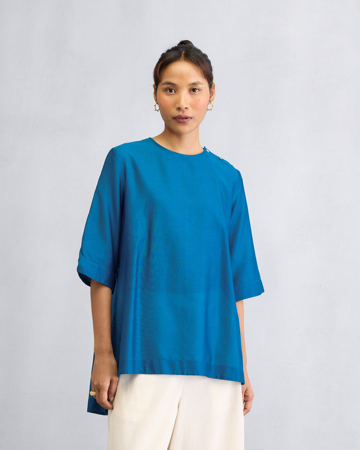 Person wearing a sapphire High Slit Top with shoulder buttons.