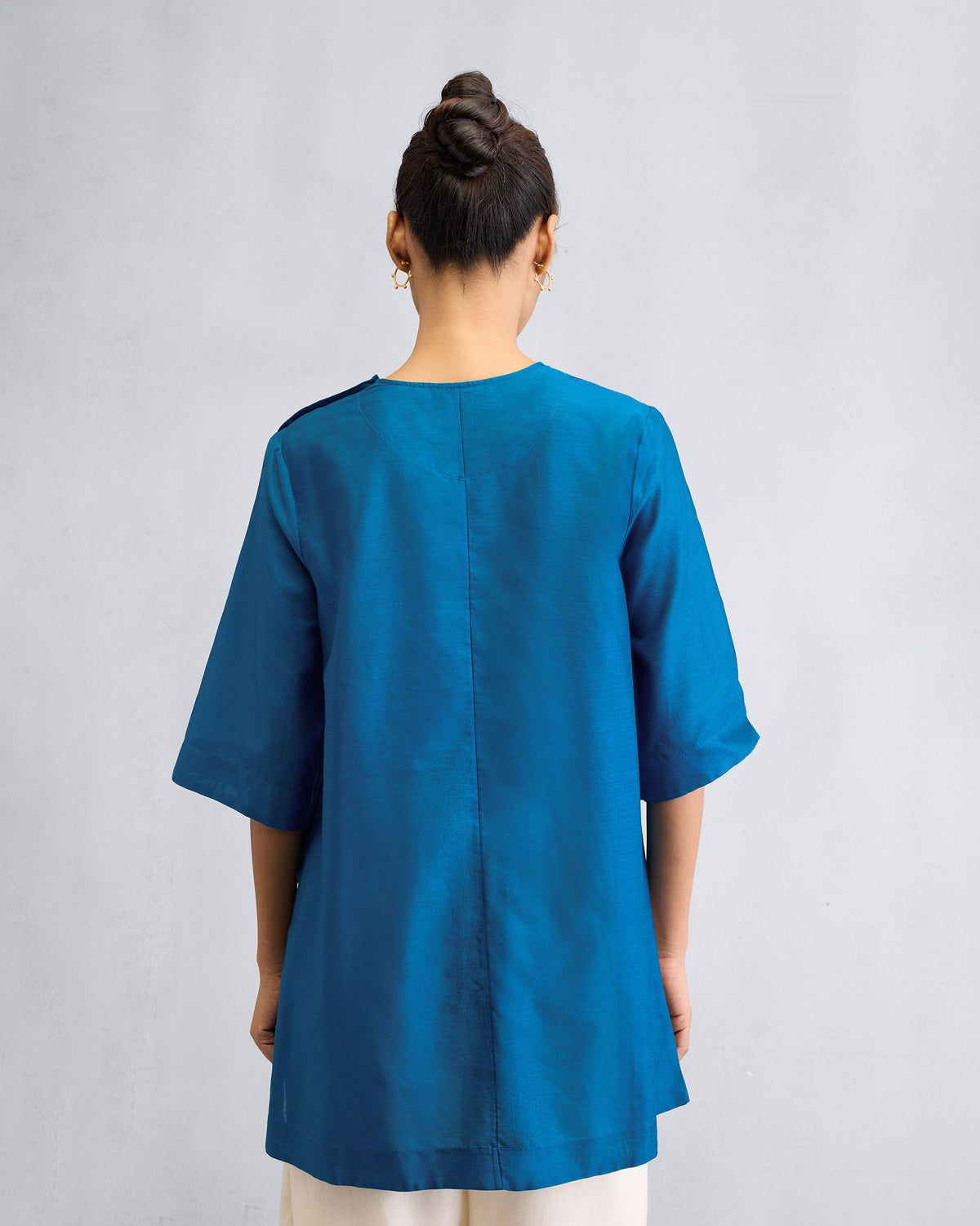 Back of a sapphire High Slit Top with a center seam.