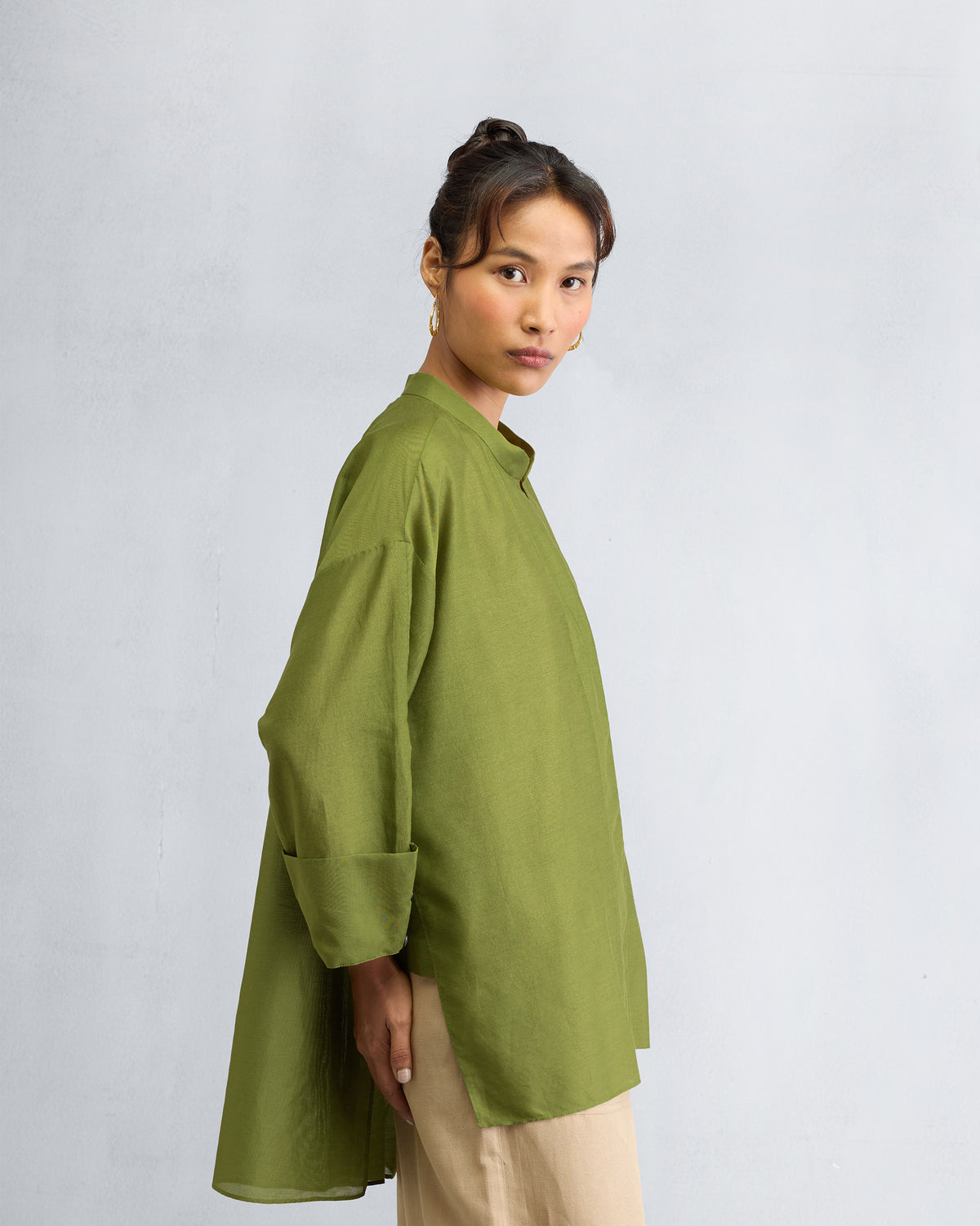 Side view of an olive Cirrus shirt showing the high-low hem.