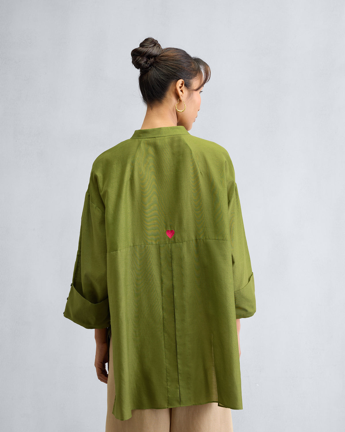 Back of an olive Cirrus shirt with a pink heart embroidery.