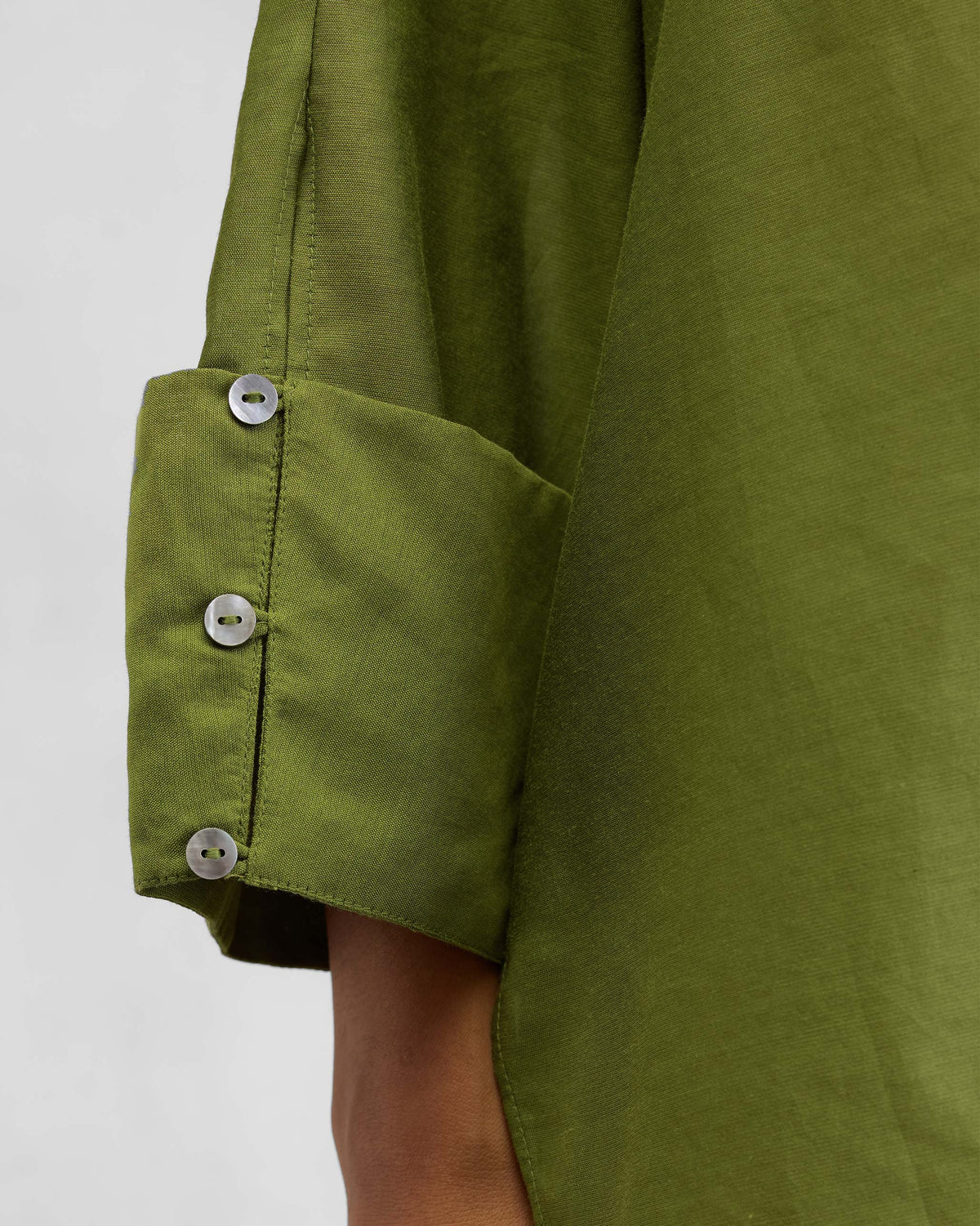 Close-up of white cuff buttons on an olive Cirrus shirt.