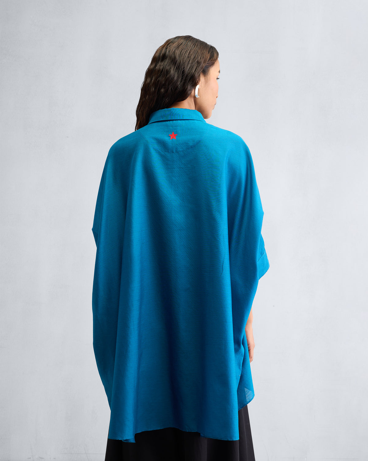 Back of a sapphire Hala tunic with a red embroidered star below the collar.