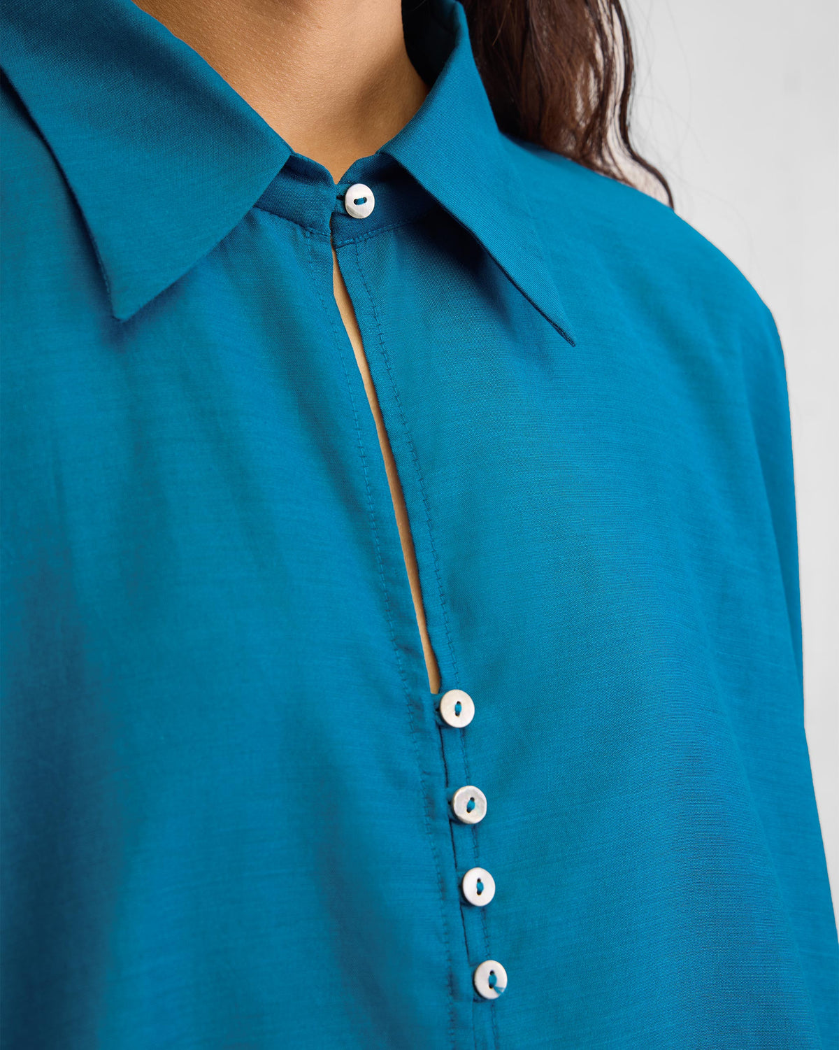 Close-up of the sapphire Hala tunic collar and white button placket.