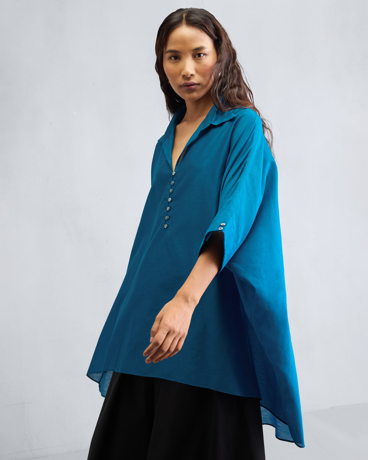 Sapphire Hala tunic with a deep V-neck, white buttons, and wide sleeves.