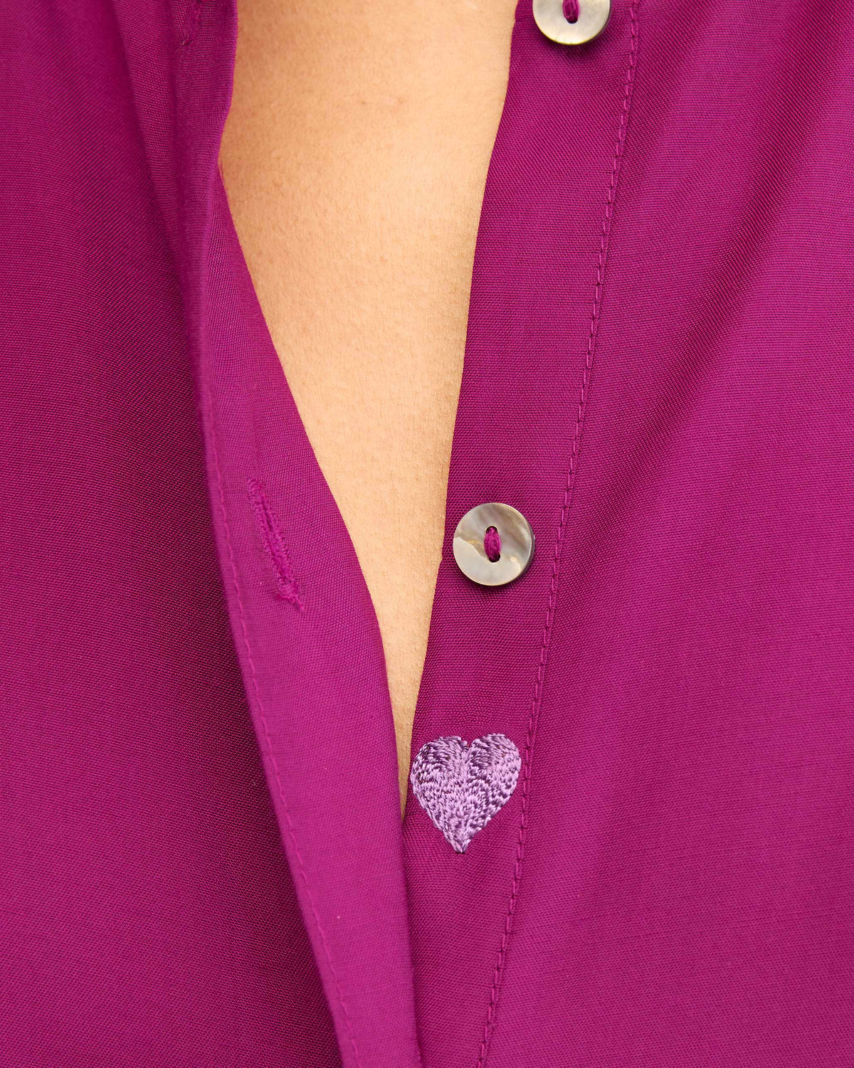 Close-up of a lavender heart on a mulberry mandarin collar top.