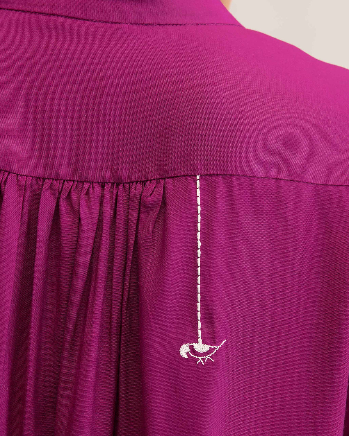 Close-up of a white parrot on a mulberry mandarin collar top.