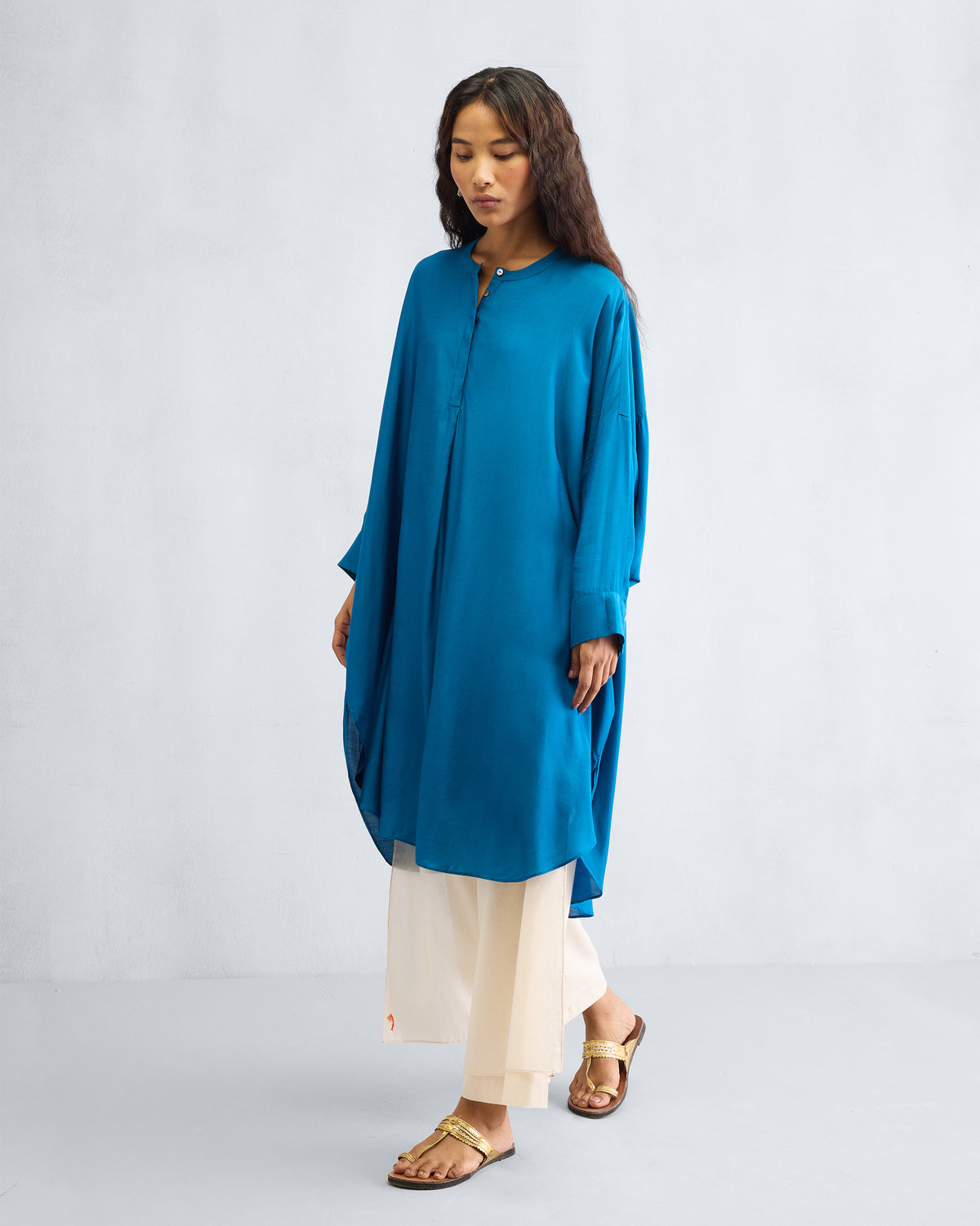 Person wearing a teal Lazy Sunday tunic with a curved hem.