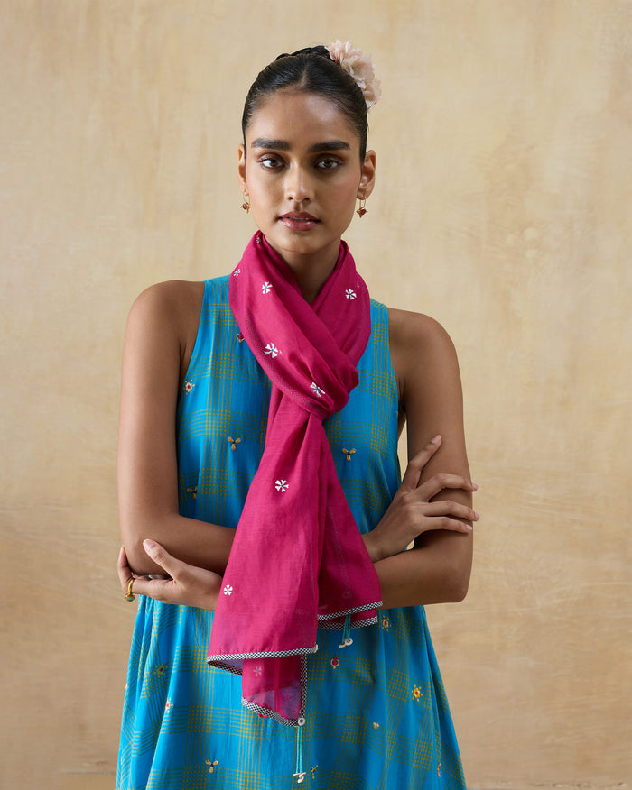 Person wearing a berry Jashn scarf with small white embroidered flowers.