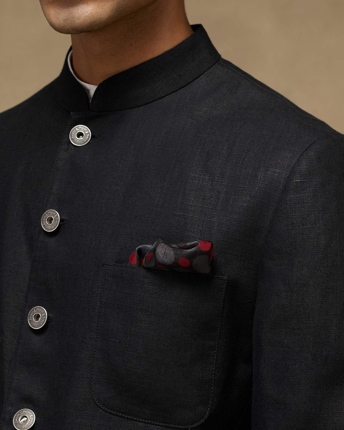 Black pocket square with red polka dots tucked in a black jacket pocket.
