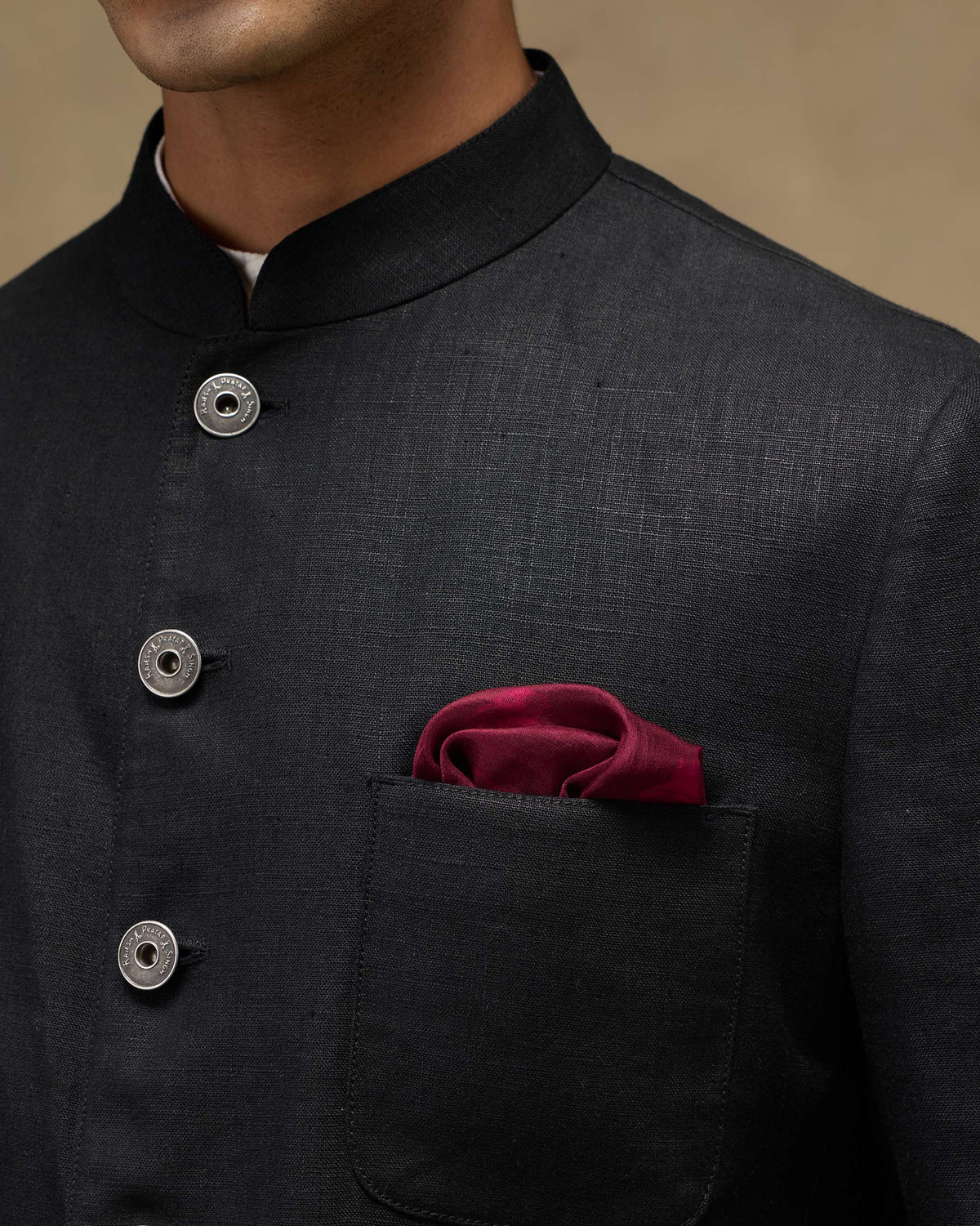 Maroon silk pocket square in a soft puff fold in a black jacket pocket.