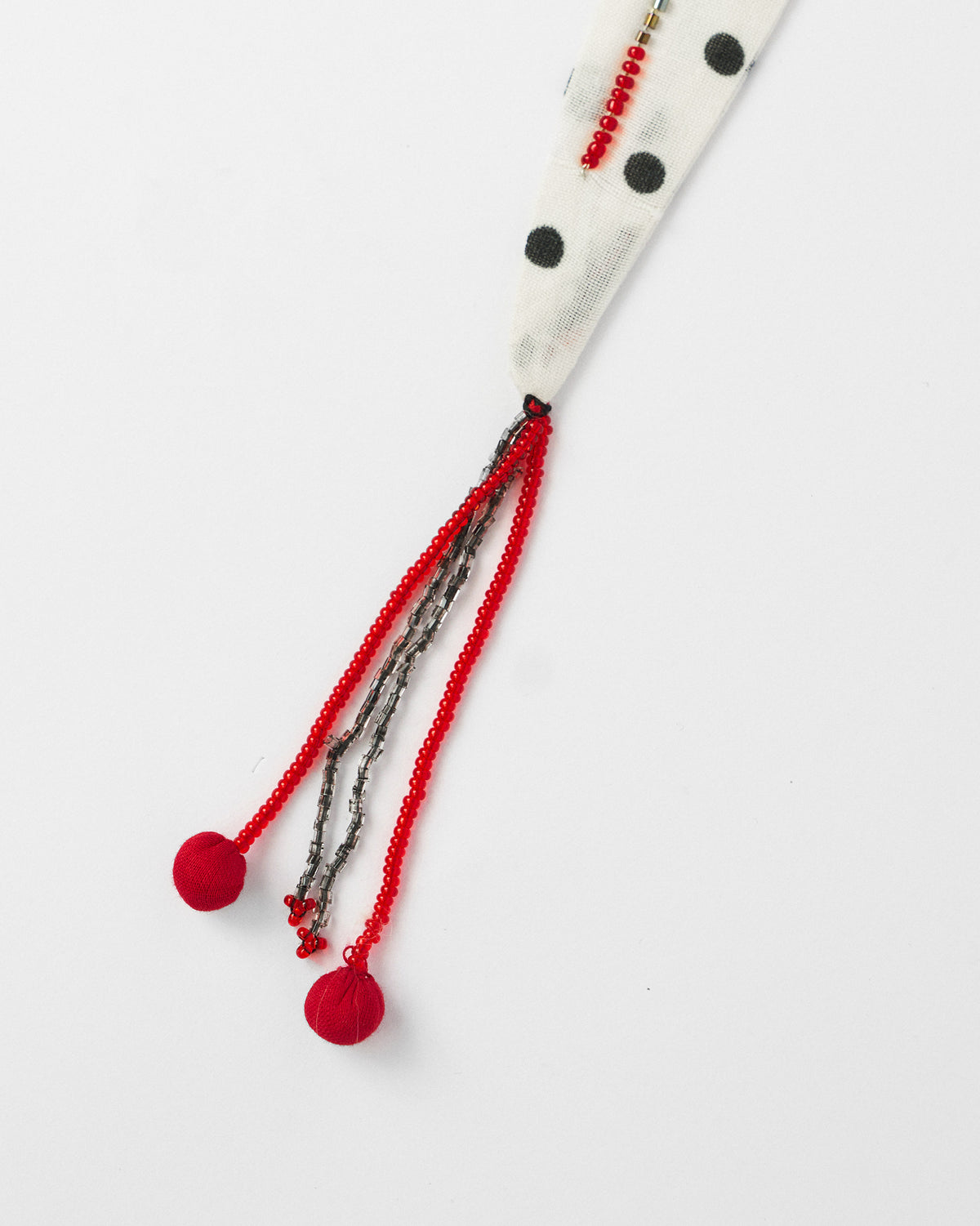Close-up of red and grey beaded tassels on an ivory polka-dot scarf tip.