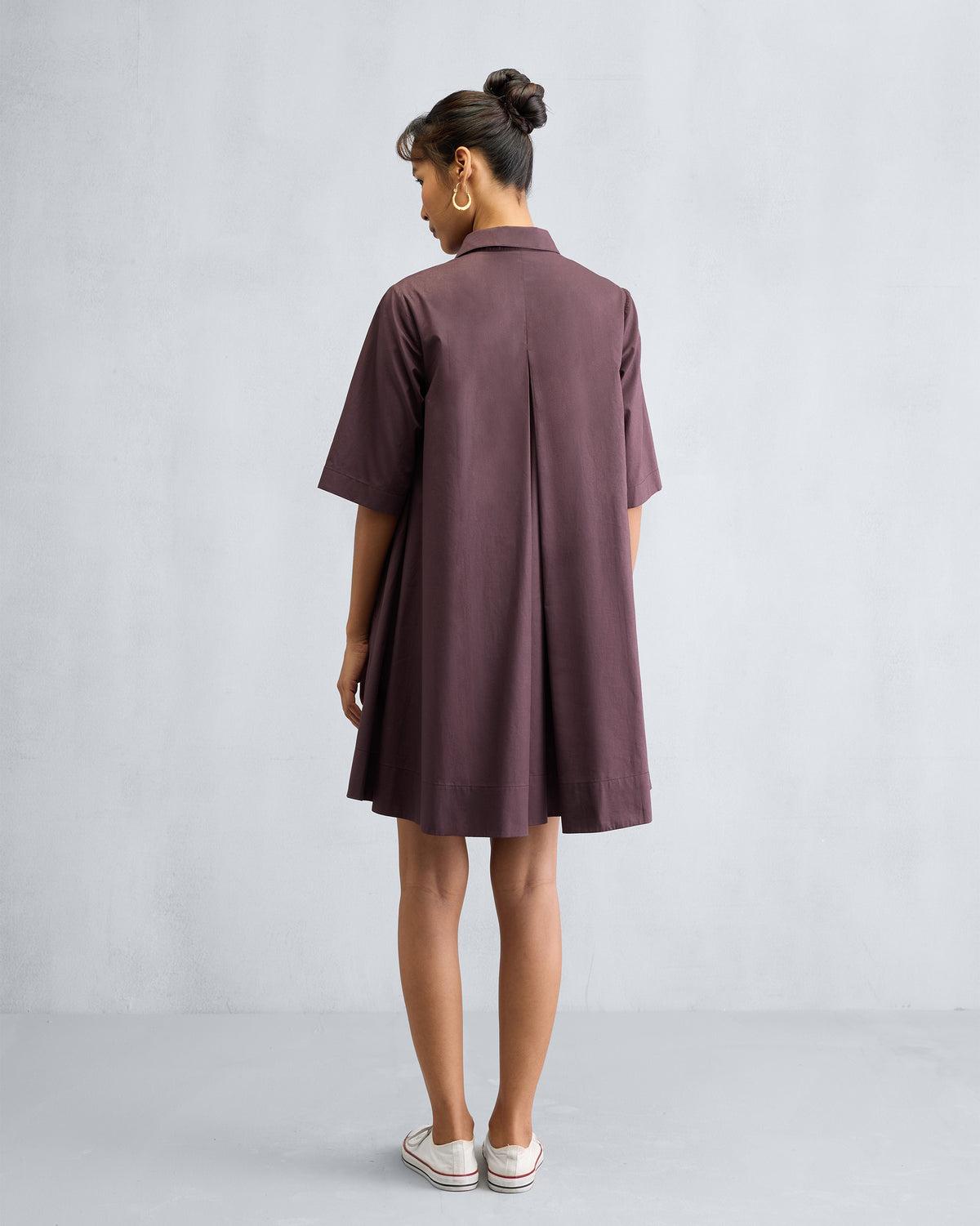 Back of a chocolate plum A-line short dress showing a deep inverted pleat.