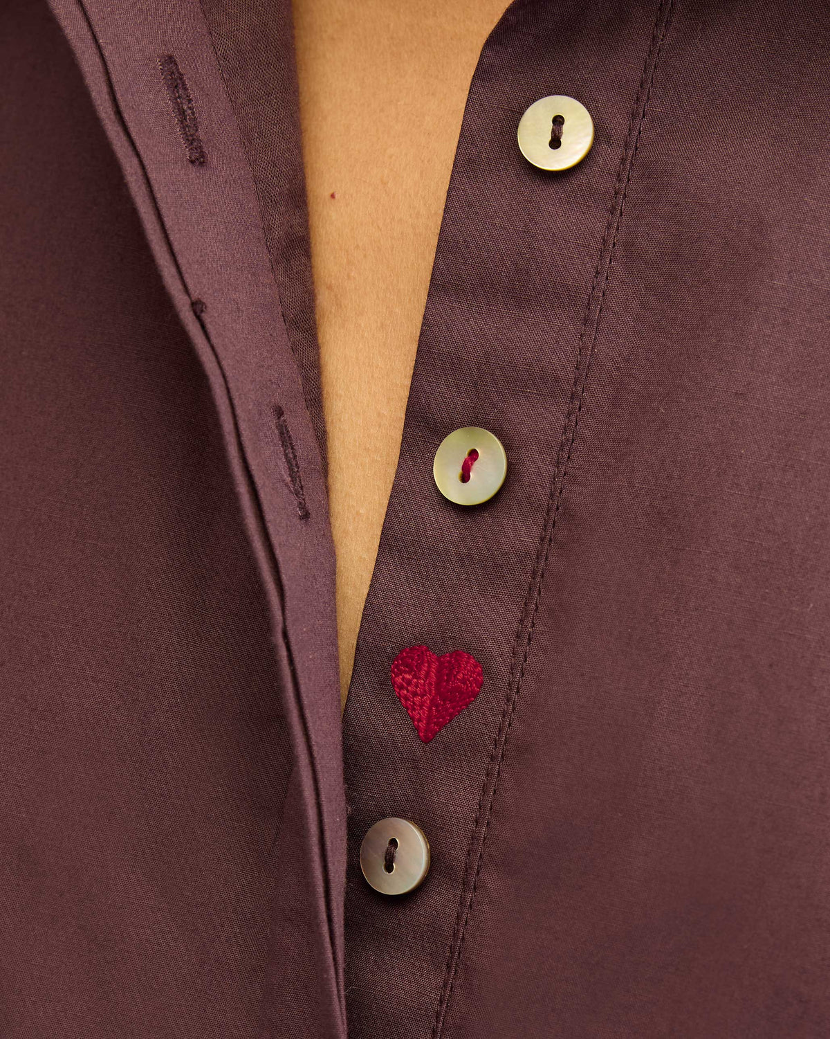 Close-up of a chocolate plum dress placket with buttons and a red heart.