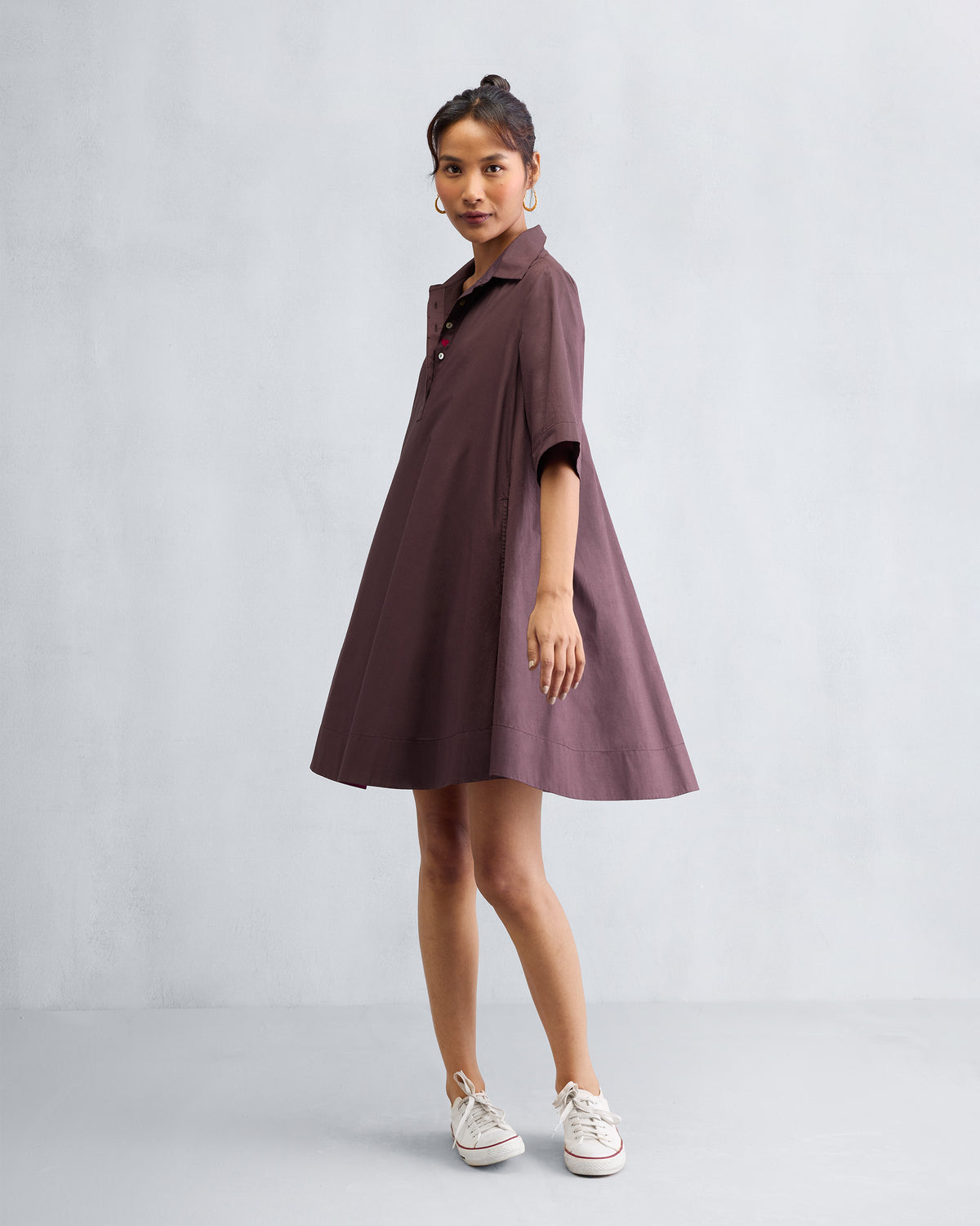 Person wearing a chocolate plum A-line short dress with elbow-length sleeves.