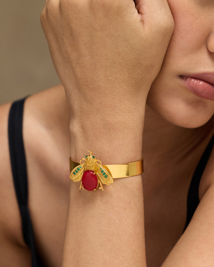 Gold Bug bracelet with a red stone insect motif worn on a wrist.