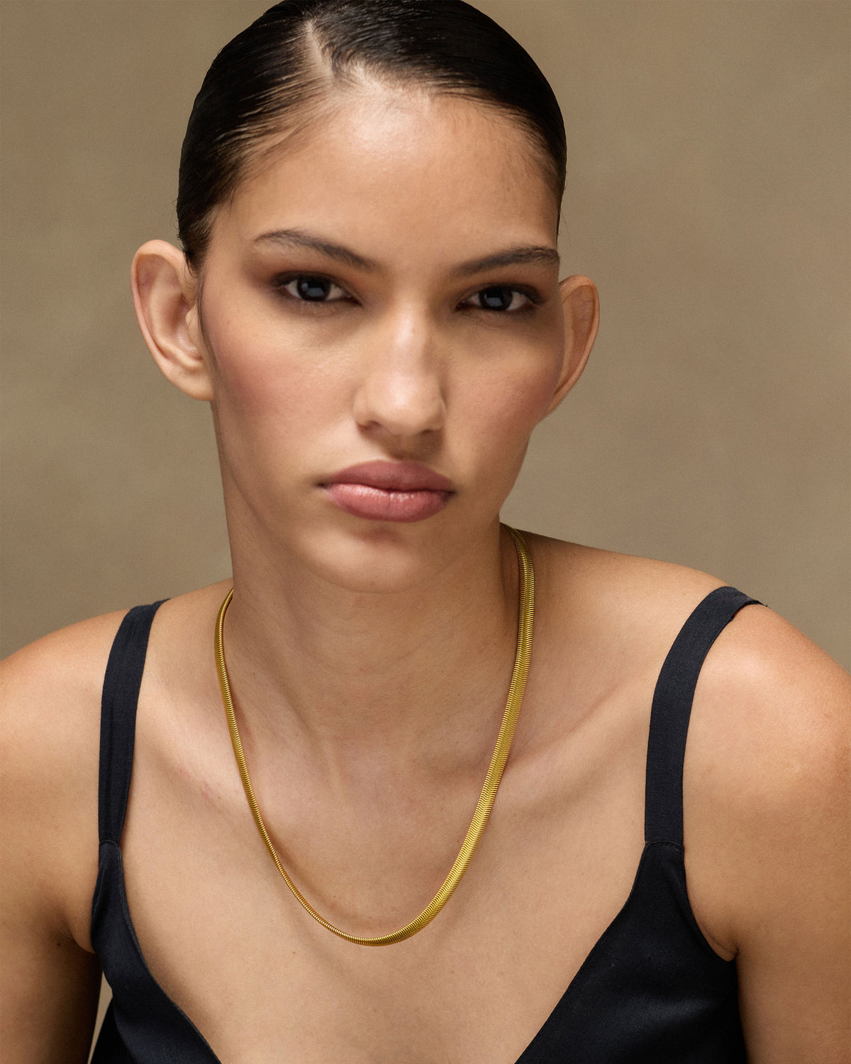 Person wearing a flat gold herringbone chain.