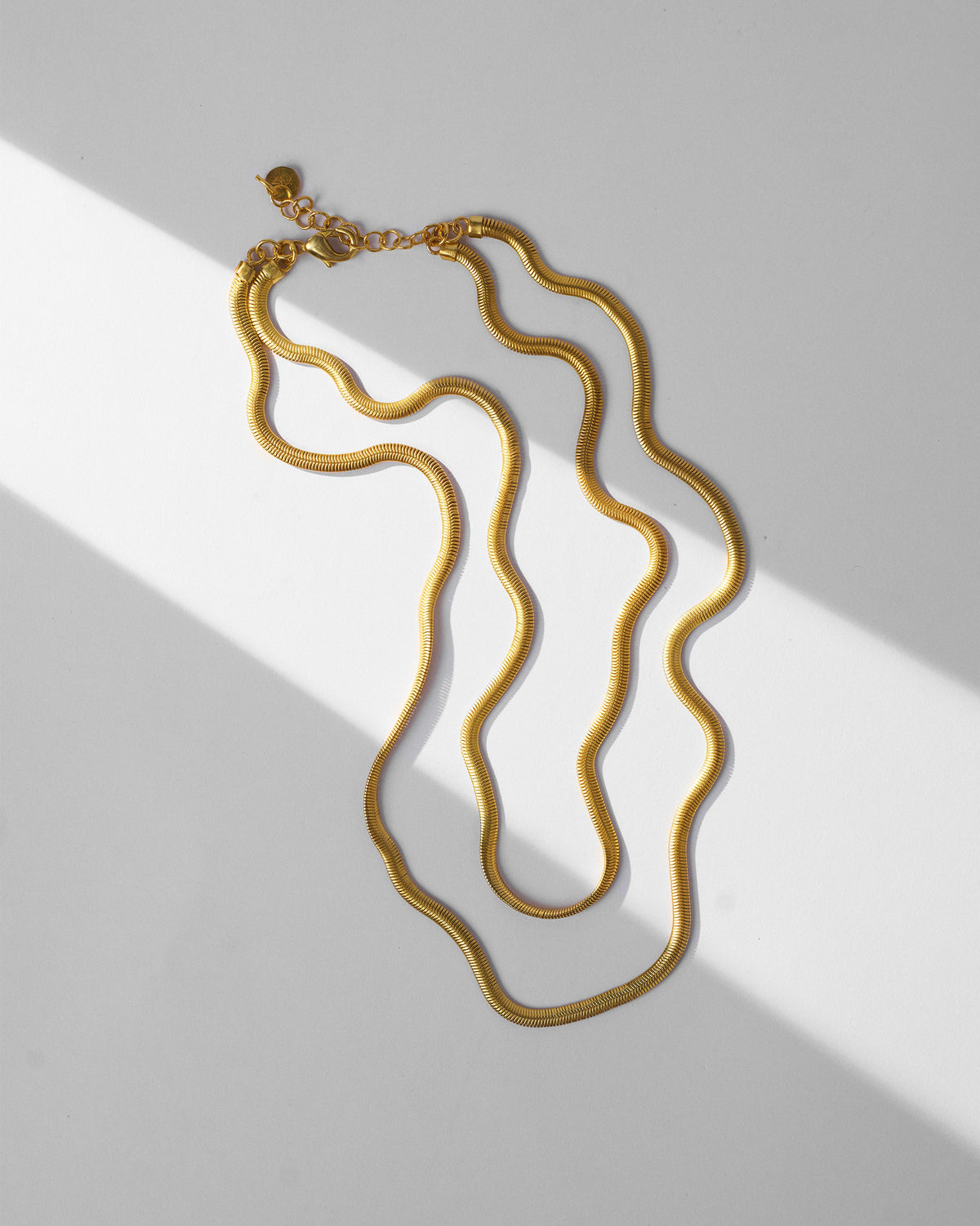 Gold Layered Herringbone Chain laid flat, showing two wavy strands and clasp.