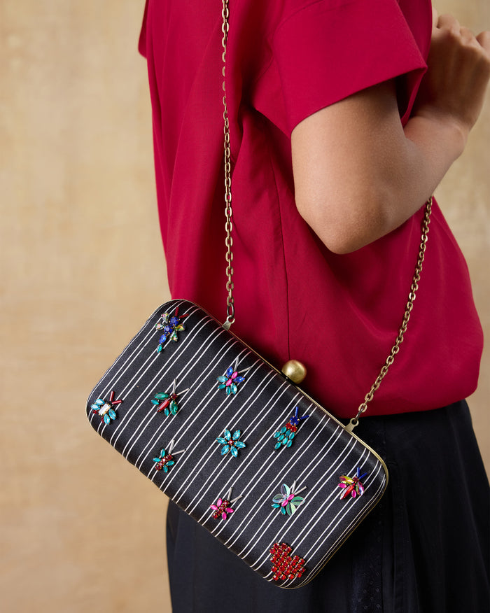 Black embroidered Martini Clutch worn on a gold chain.