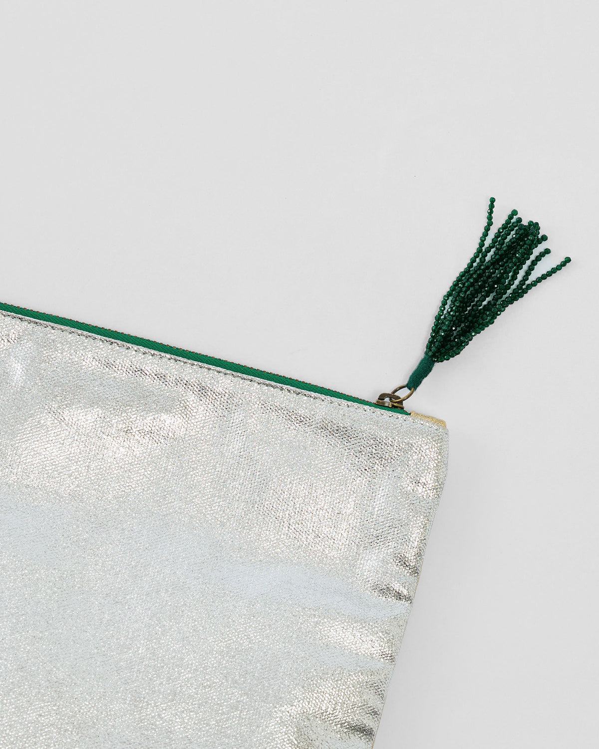 Close-up of the green beaded tassel on a silver Fold Over Clutch.