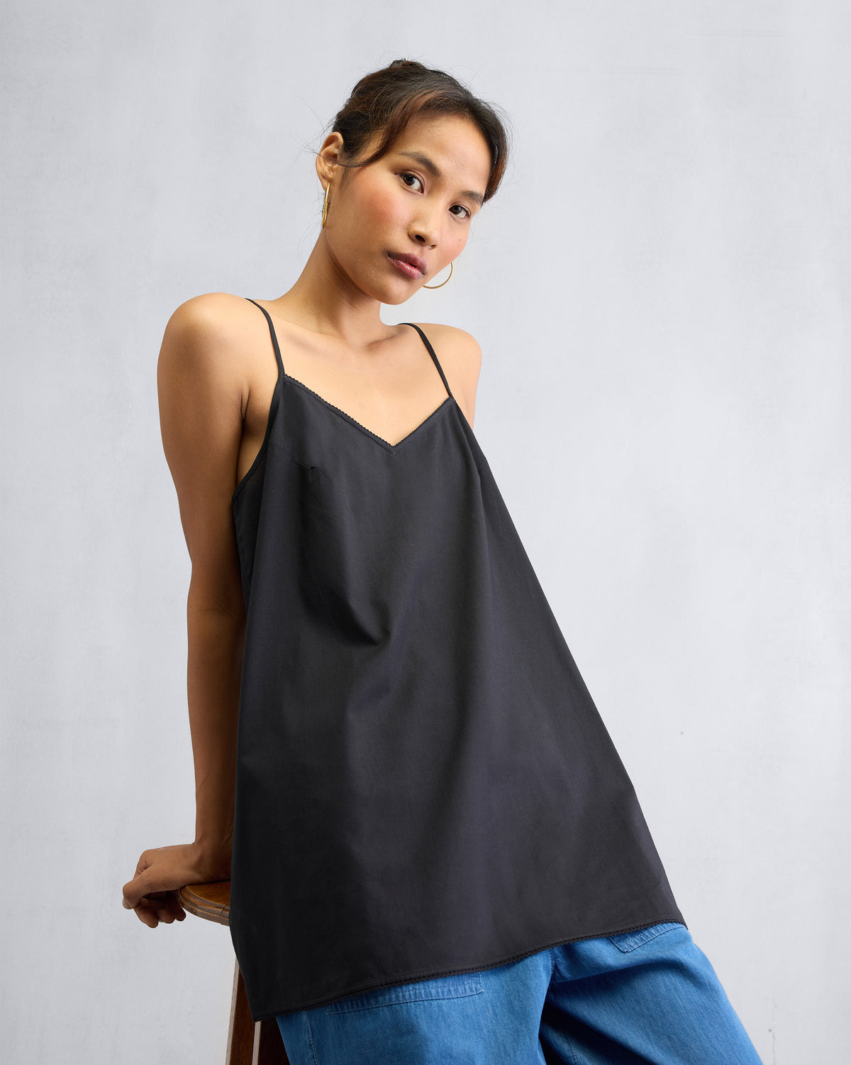 Person wearing a black Afra Camisole with thin spaghetti straps.