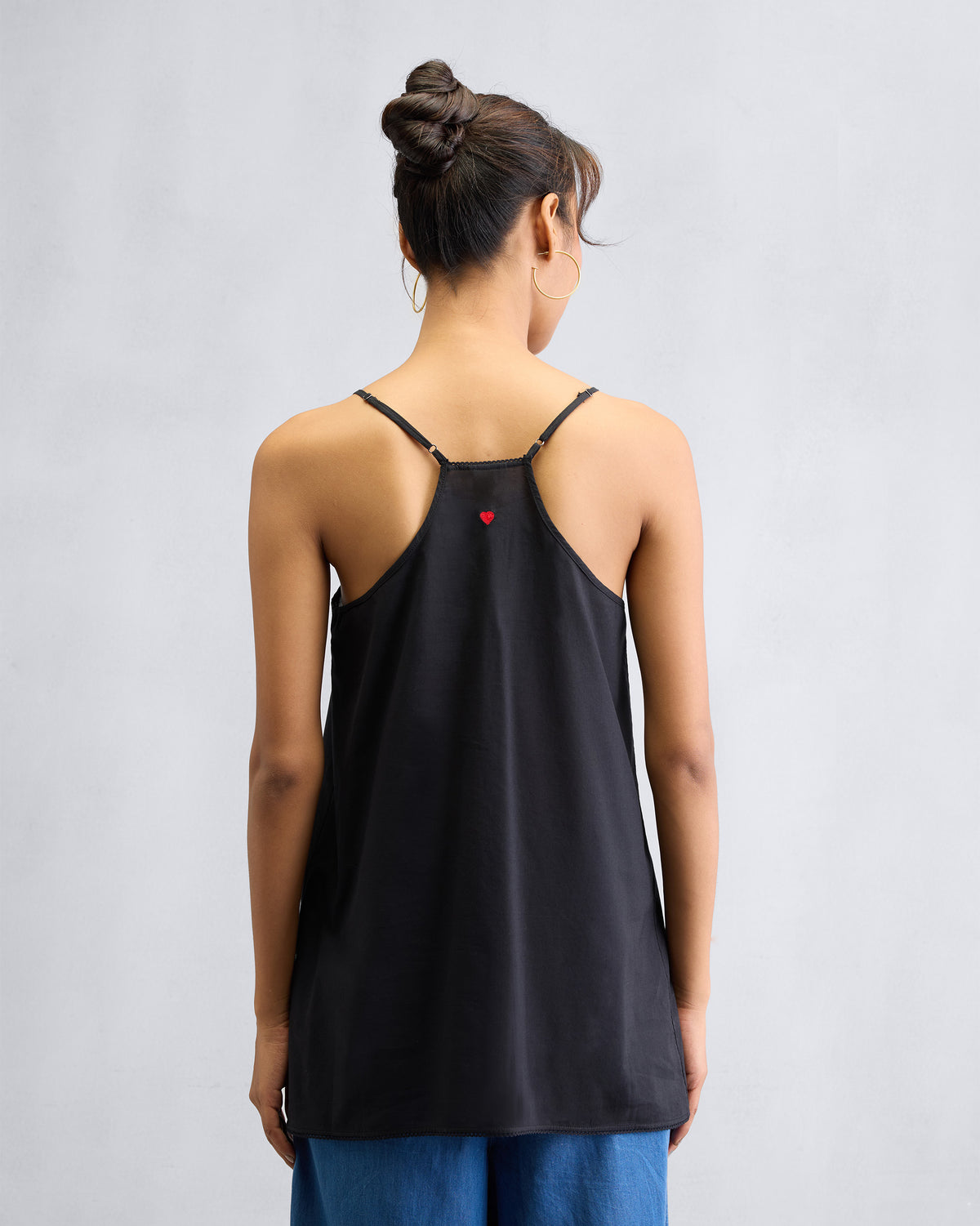 Back of a black Afra Camisole with a red heart embroidered at the centre.