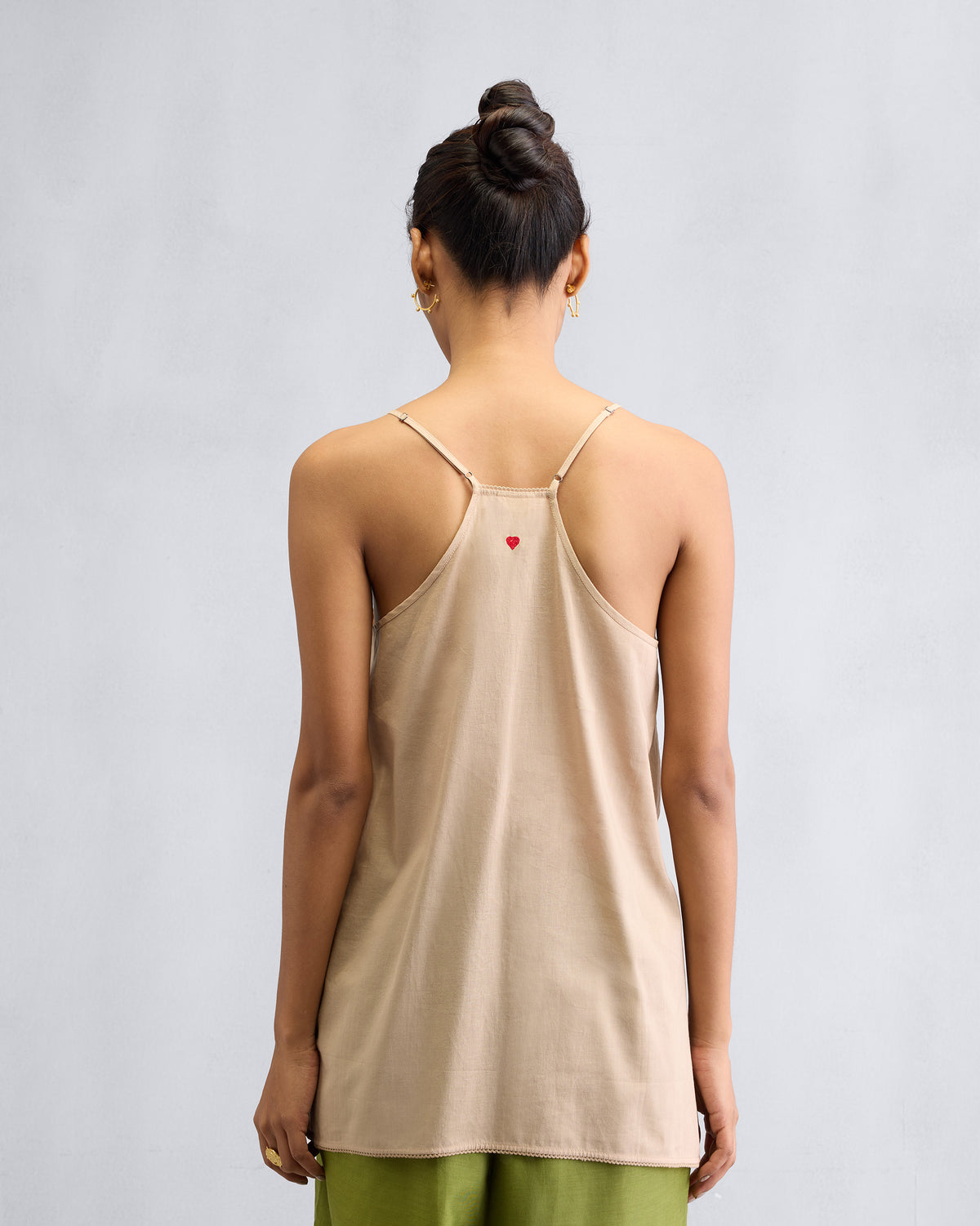Back of a sand Afra Camisole with a red heart embroidered at the centre.