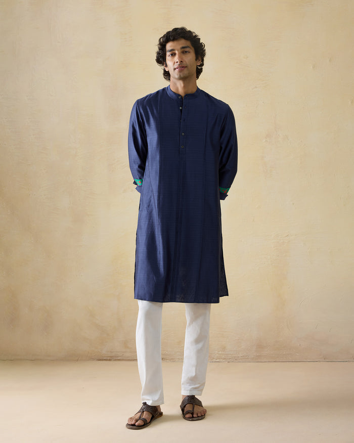 Person wearing a navy Naaz kurta with band collar and contrast cuff trim.