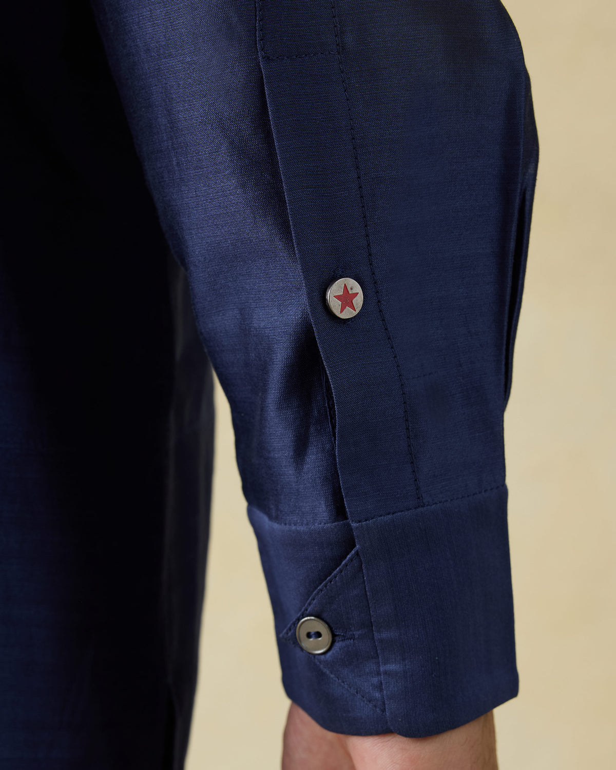 Close-up of a red star cuff button on a navy Naaz kurta.