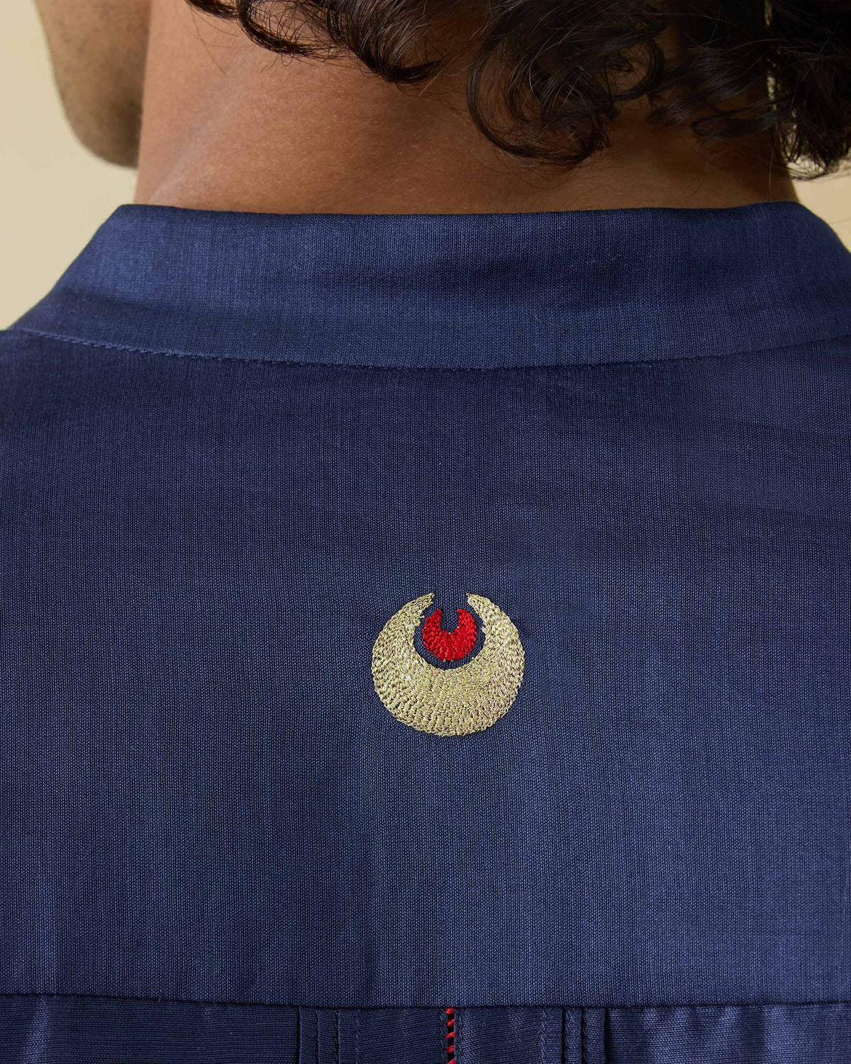 Close-up of a crescent motif on the back of a navy Naaz kurta.