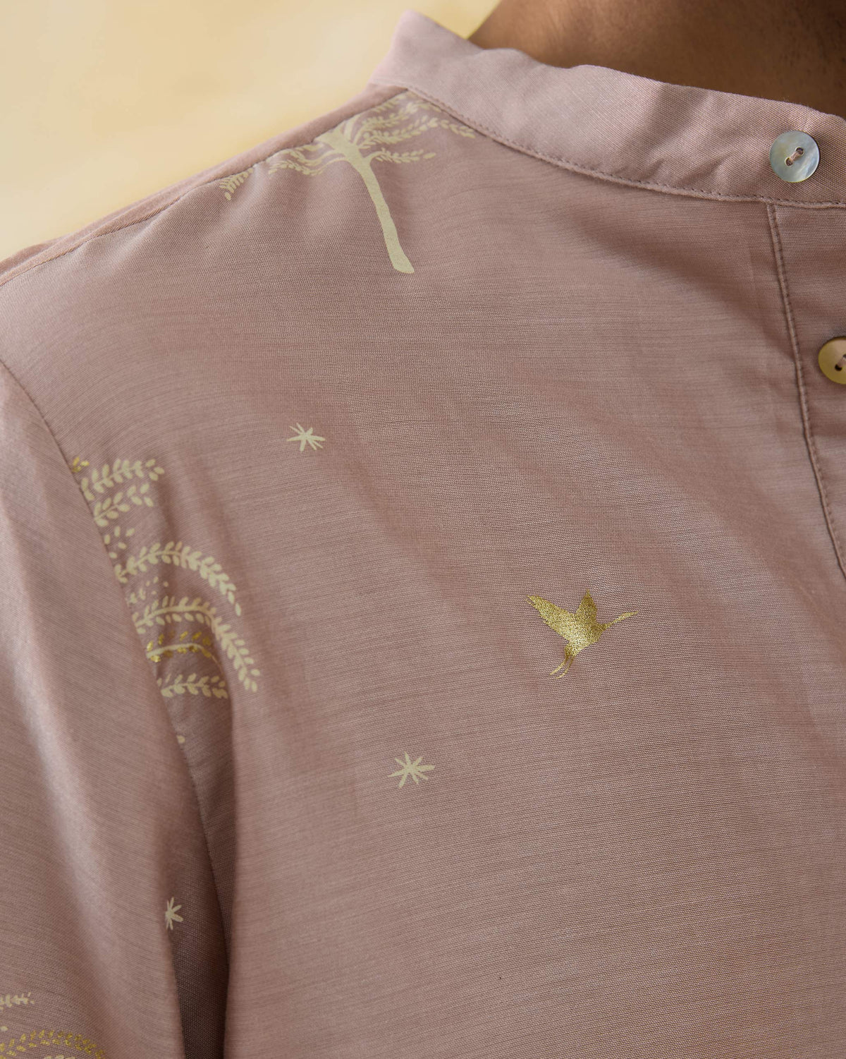 Close-up of a light pink Bageecha kurta showing gold bird and star motifs.