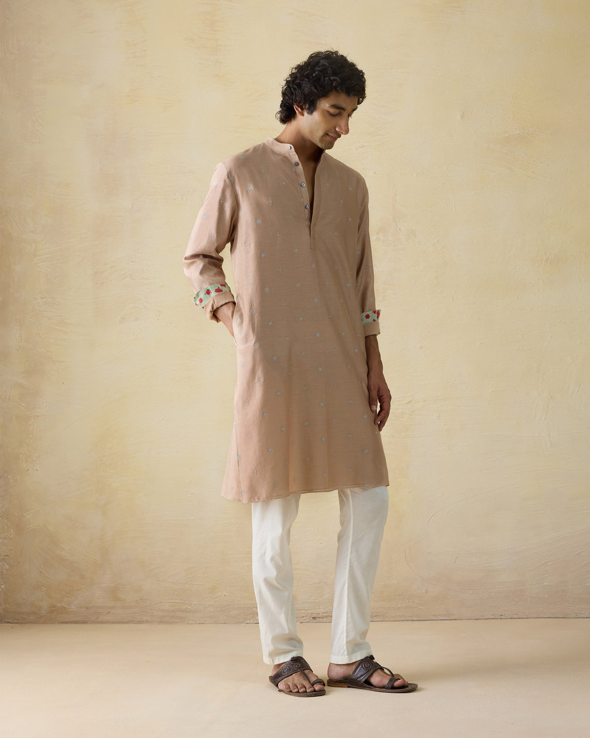 Light beige neckband kurta with floral cuff lining worn at a side angle.