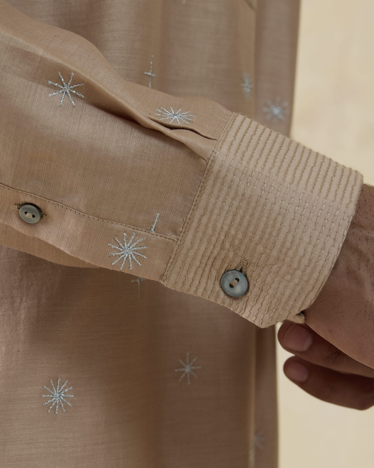 Close-up of a beige neckband kurta sleeve with starburst embroidery.