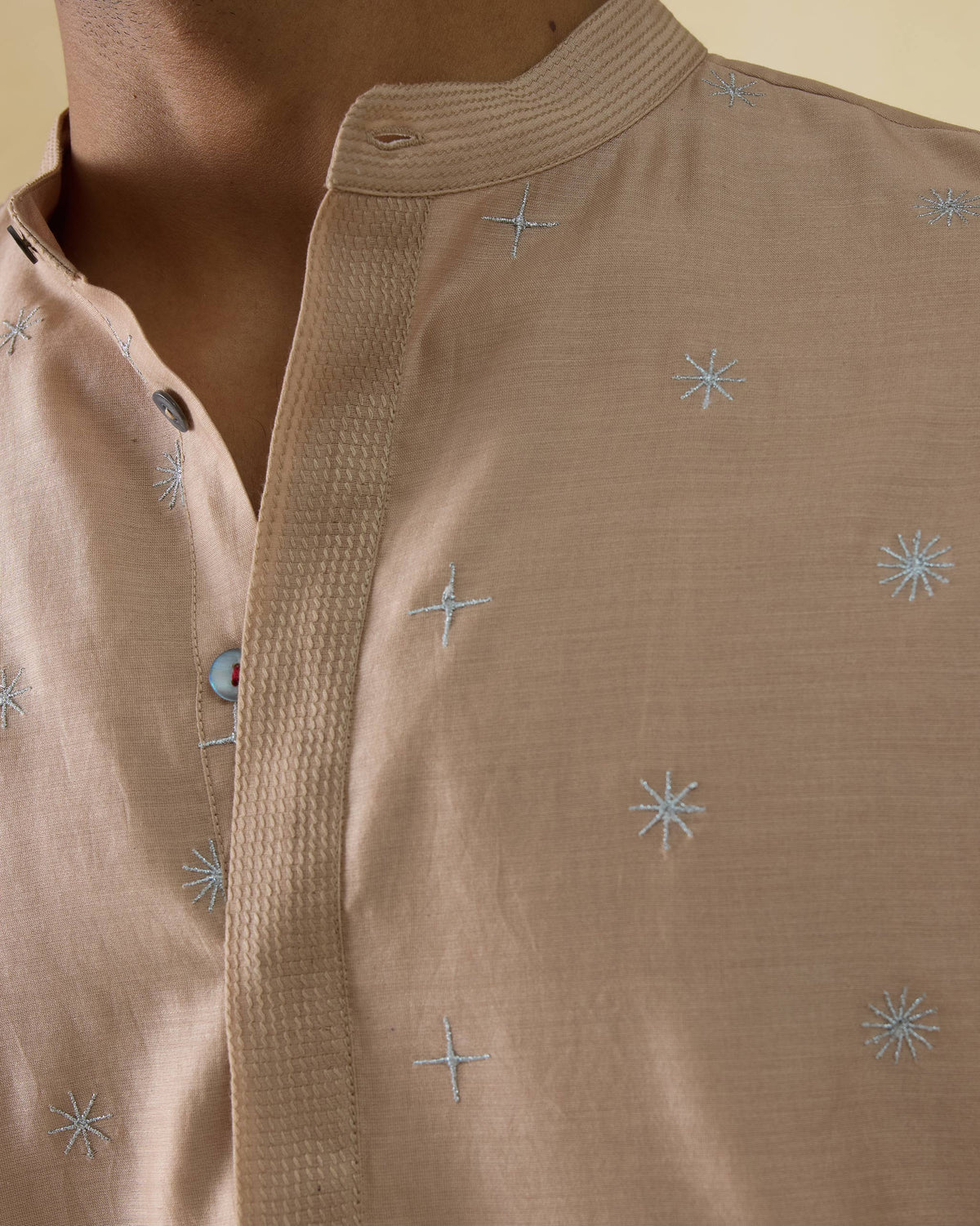 Close-up of a light beige neckband kurta showing blue star embroidery.