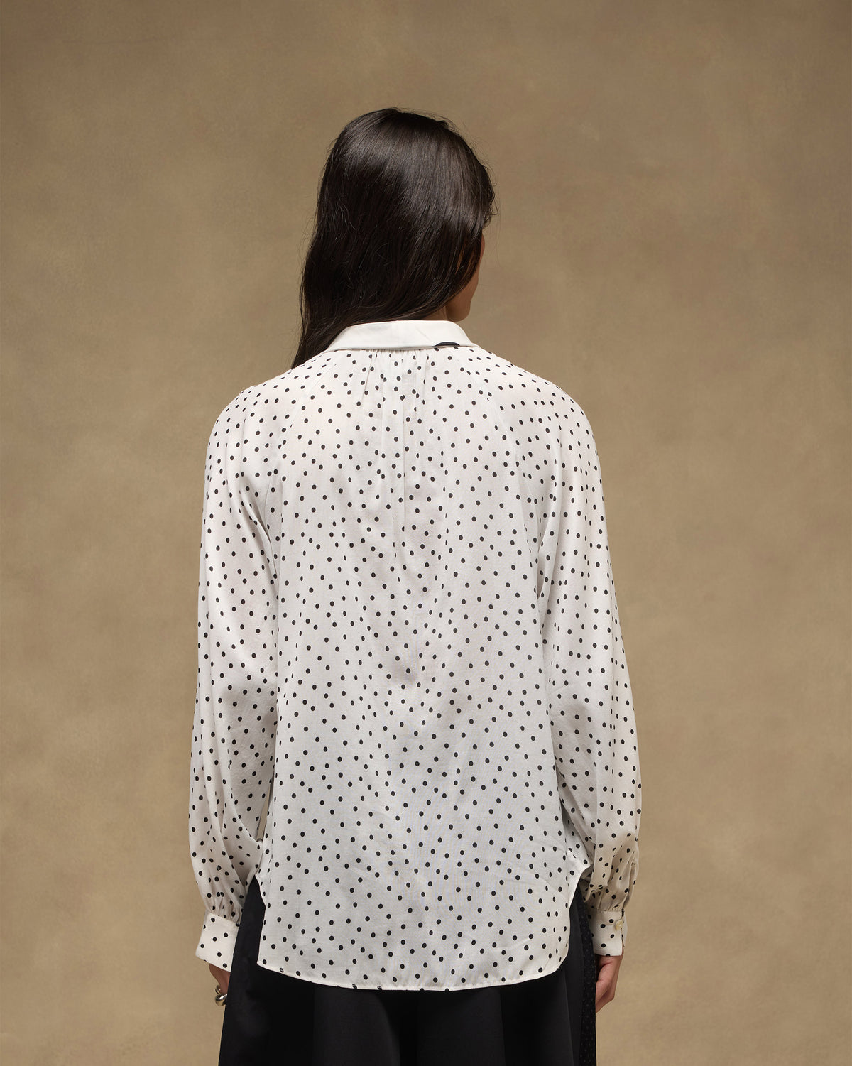 Back of an ivory and black polka-dot Whirl tie-up top with a curved hem.