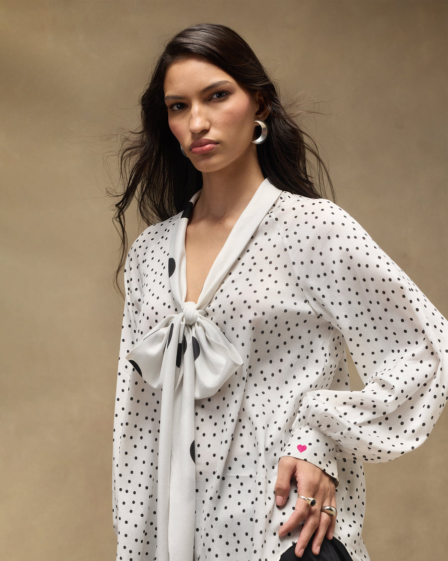 The Whirl Tie Up Top worn loose, with full sleeves and the bow at the neck.