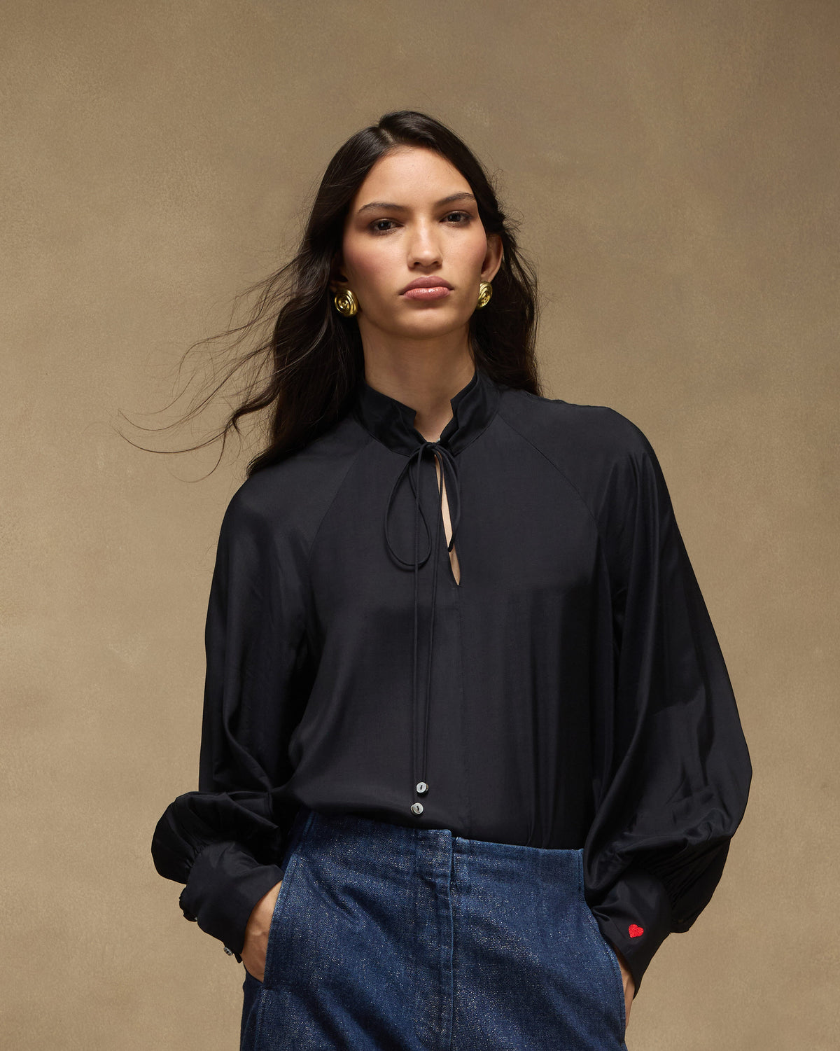Person wearing a black high-neck top with keyhole ties and full sleeves.