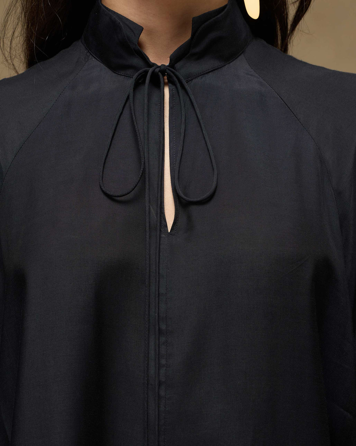 Close-up of a black top collar with a keyhole and fabric ties.